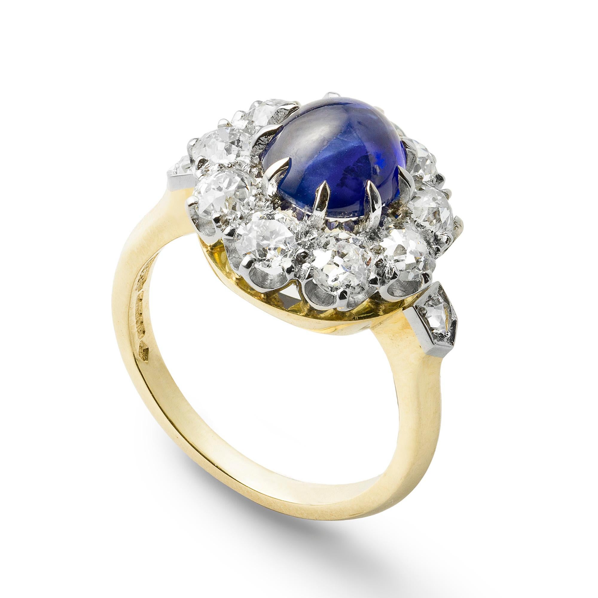 A sapphire and diamond cluster ring, the cabochon-cut sapphire weighing 2.86 carats, surrounded by nine old brilliant-cut diamonds weighing 1.88 carats in total, all claw set in platinum, to a gold mount with rose-cut diamond set shoulders,