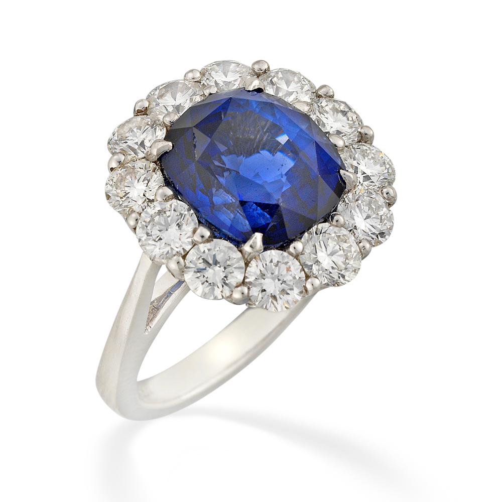 A sapphire and diamond cluster ring, the cushion-cut sapphire weighing 8.32 carats accompanied by  Gem and Pearl Lab Cert stating that the sapphire is from Madagascar with no signs of heating, four claw-set to the centre of a twelve round