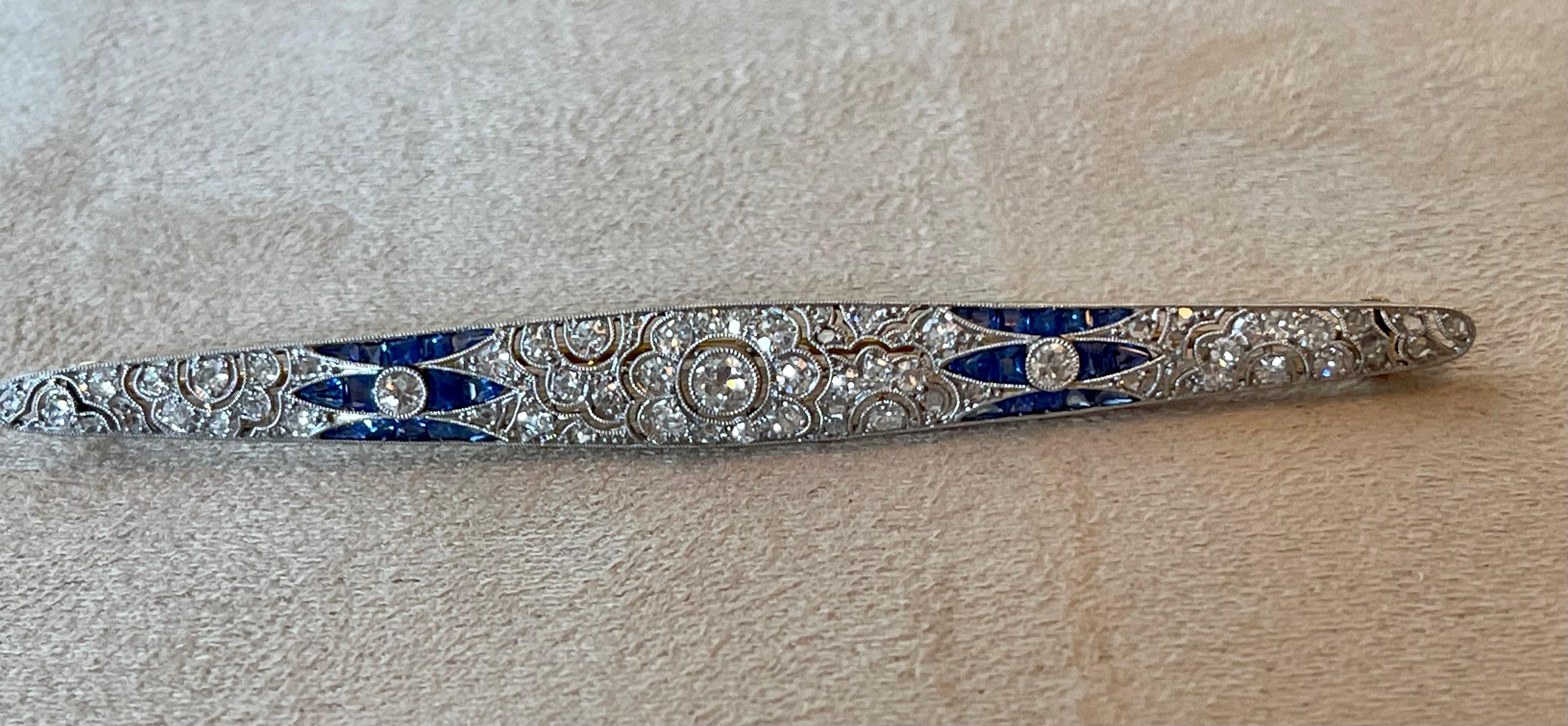 Lovely longish  bar brooch, in 18 K yellow Gold and Platinum, set with 62 brilliant cut Diamonds weighing approximately 0.90 ct and calibré cut Sapphires in an exquuisite filigree open work setting with fine milgrain. 
8 cm long and 0.78 cm wide.