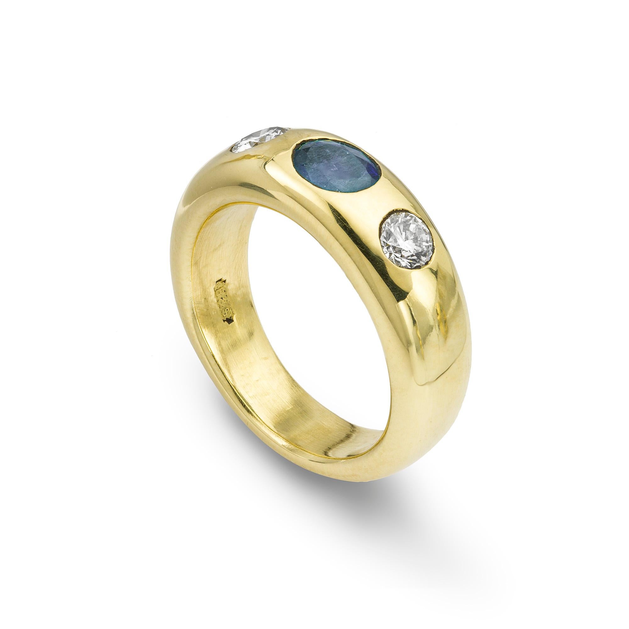 A sapphire and diamond gold gypsy ring, the oval faceted sapphire, weighing 0.80 carats, set horizontally with a round brilliant-cut diamond to each side, weighing a total of 0.47 carats, all gypsy set to a yellow mount with a tapering band,