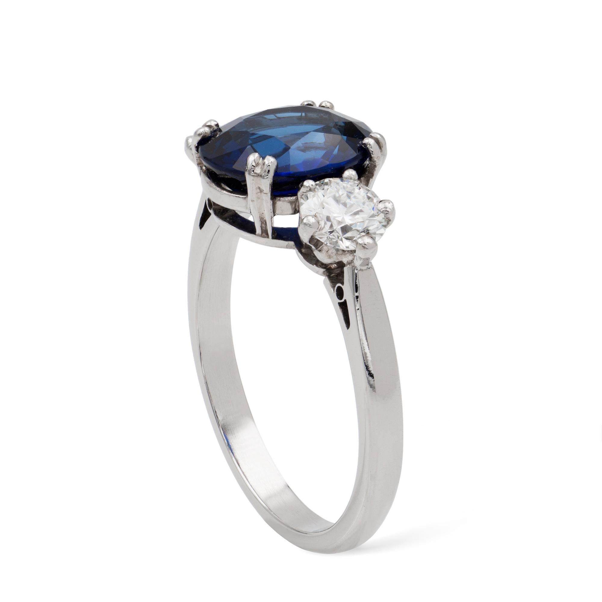 A sapphire and diamond three-stone ring, the oval-shaped sapphire, weighing 3.12 carats, set between two round brilliant-cut diamonds weighing 0.66 carats in total, all claw-set in platinum mount, hallmarked 950 platinum London 1991,  the head