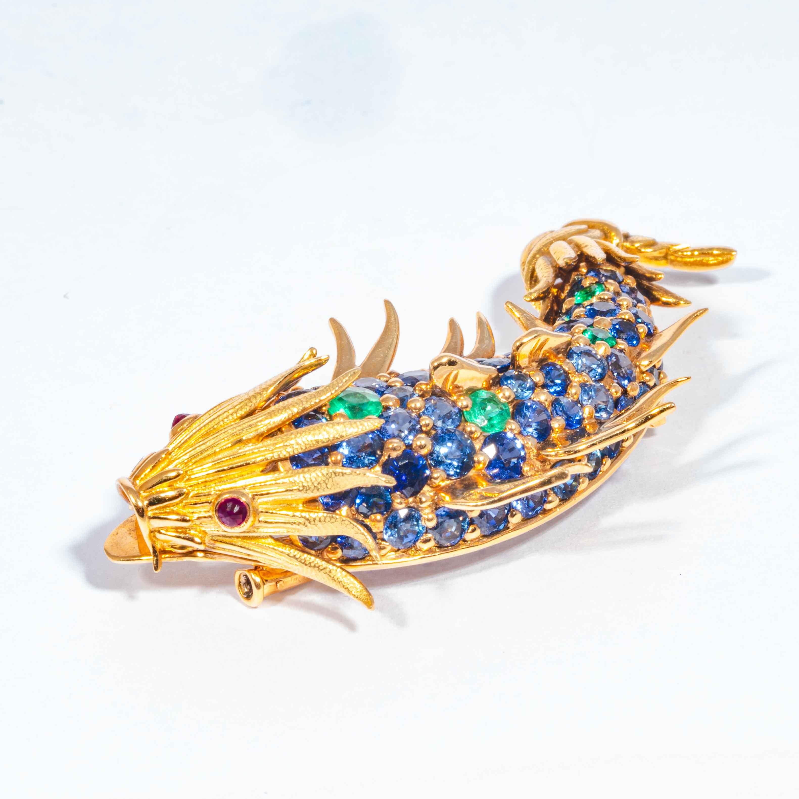 This late 20th century pin is comprised of full cut blue Ceylon sapphires, a 5 accenting green emerald fish 