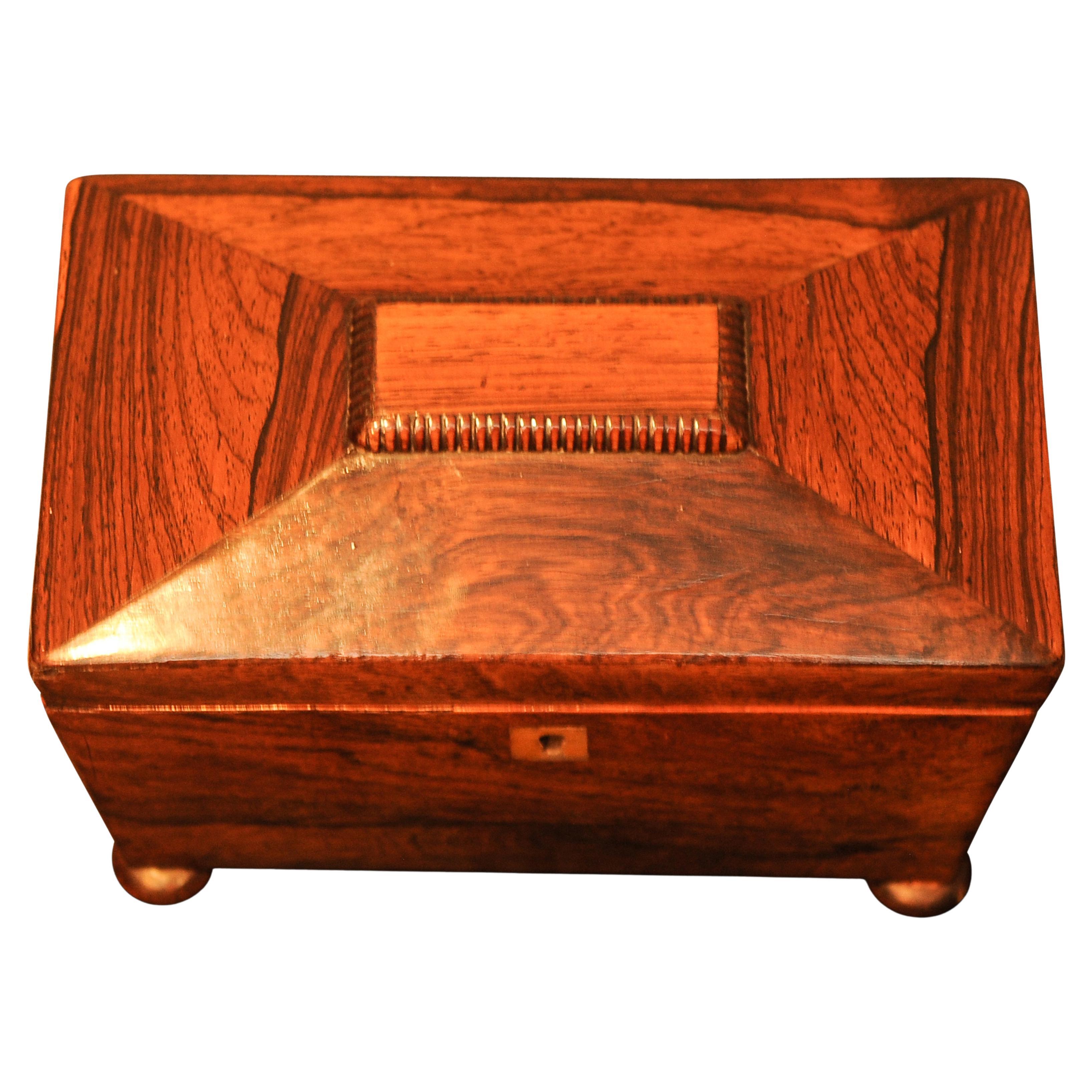 A Sarcophagus Shaped Regency Rosewood, Brass Tea Caddy With Two Separate Tea Compartments and Individual Handled Lids, Centred on Four Bun Feet Circa 1700's 

Great patina embellishing the age of the caddy.