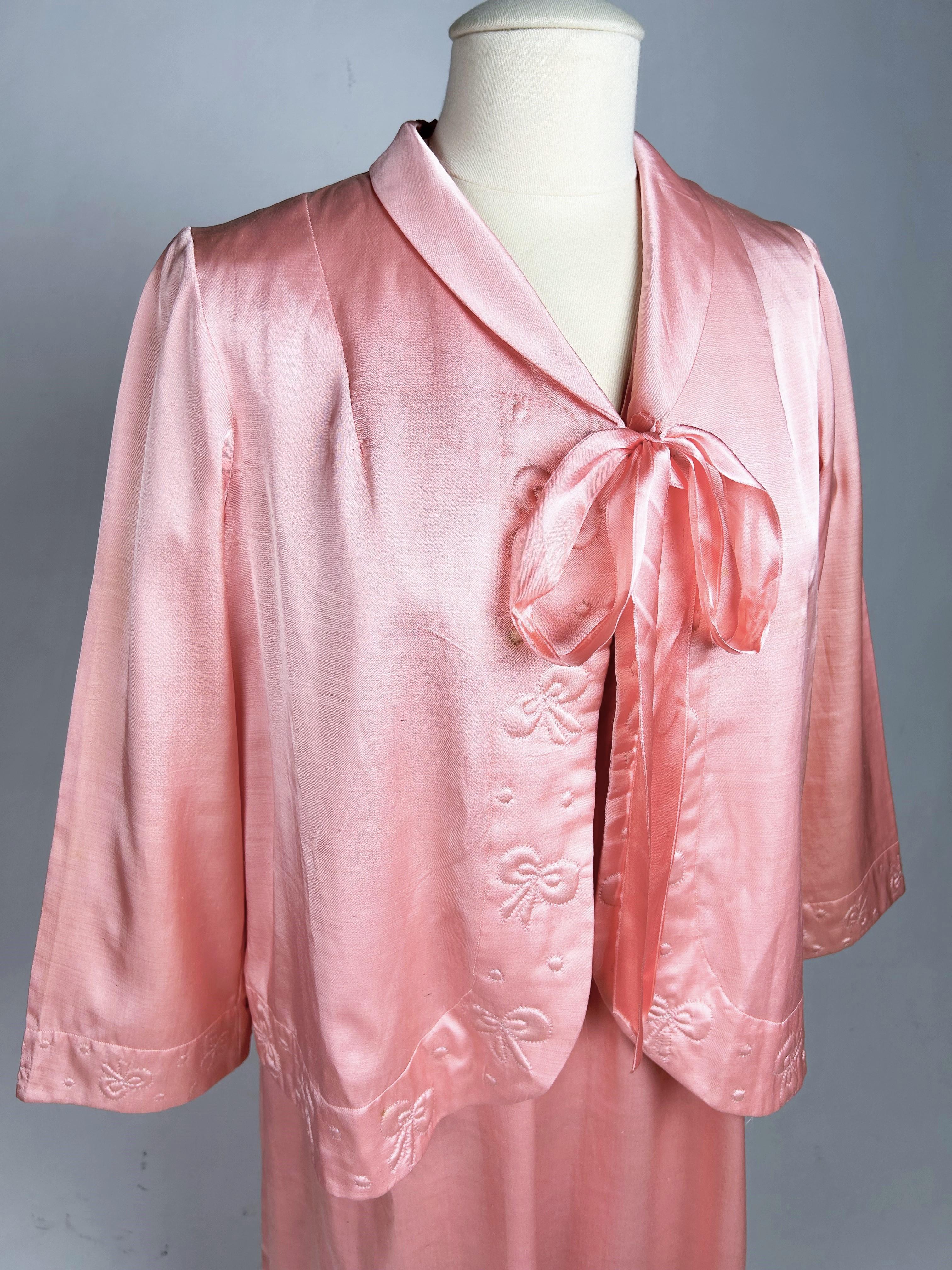 Alrededor de 1950-1960 Francia
Conjunto de noche compuesto por una camisa con cinturón y un bolero envolvente de satén rosa que data de 1950-1960. Vestido largo y amplio con pequeñas mangas globo, abrochado delante con cuatro botones de nácar.