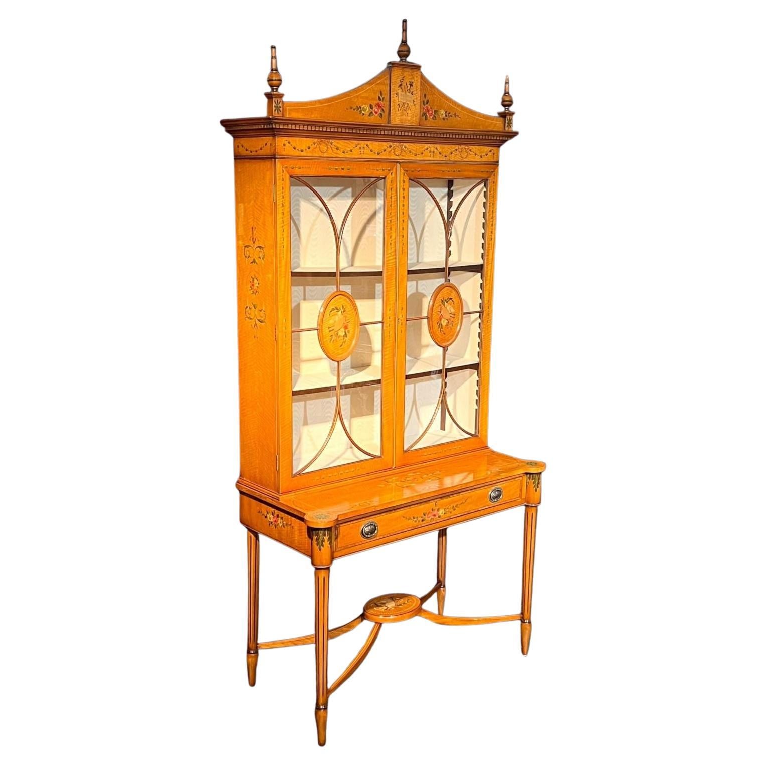 Antique hand painted satinwood cabinet on stand. Of large proportions, glazed upper cabinet with two adjustable shelves, the base with single drawer. Rich satinwood colour with hand painted accents throughout. Standing on tapering fluted legs united