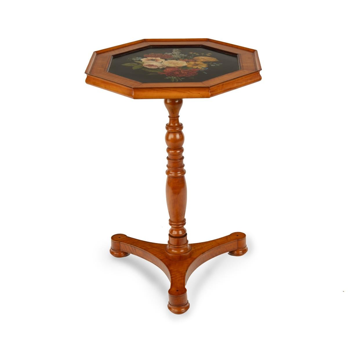 A satinwood hexagonal tilt-top table, the hexagonal top beautifully painted in polychrome with a bunch of flowers on a black ground, with purple heart and ebony stringing, on a turned baluster support on a triform base with bun feet.  Belgian, circa