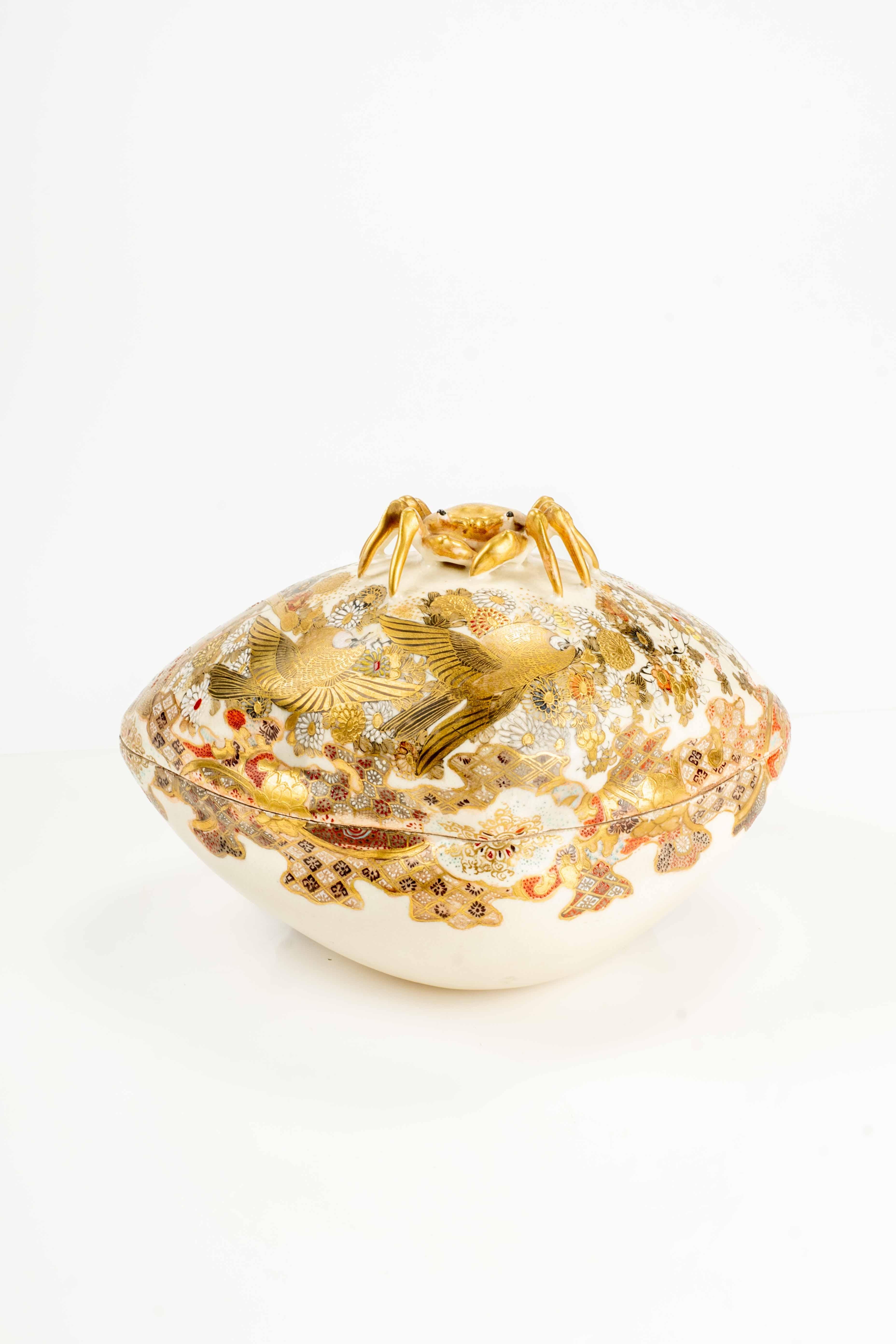 Caja japonesa de cerámica Satsuma modelada en forma de concha hamaguri (almeja japonesa tradicionalmente asociada a temas de unión), con un cangrejo dorado como asa. 

El exterior está decorado en esmaltes policromados y oro con motivos florales y