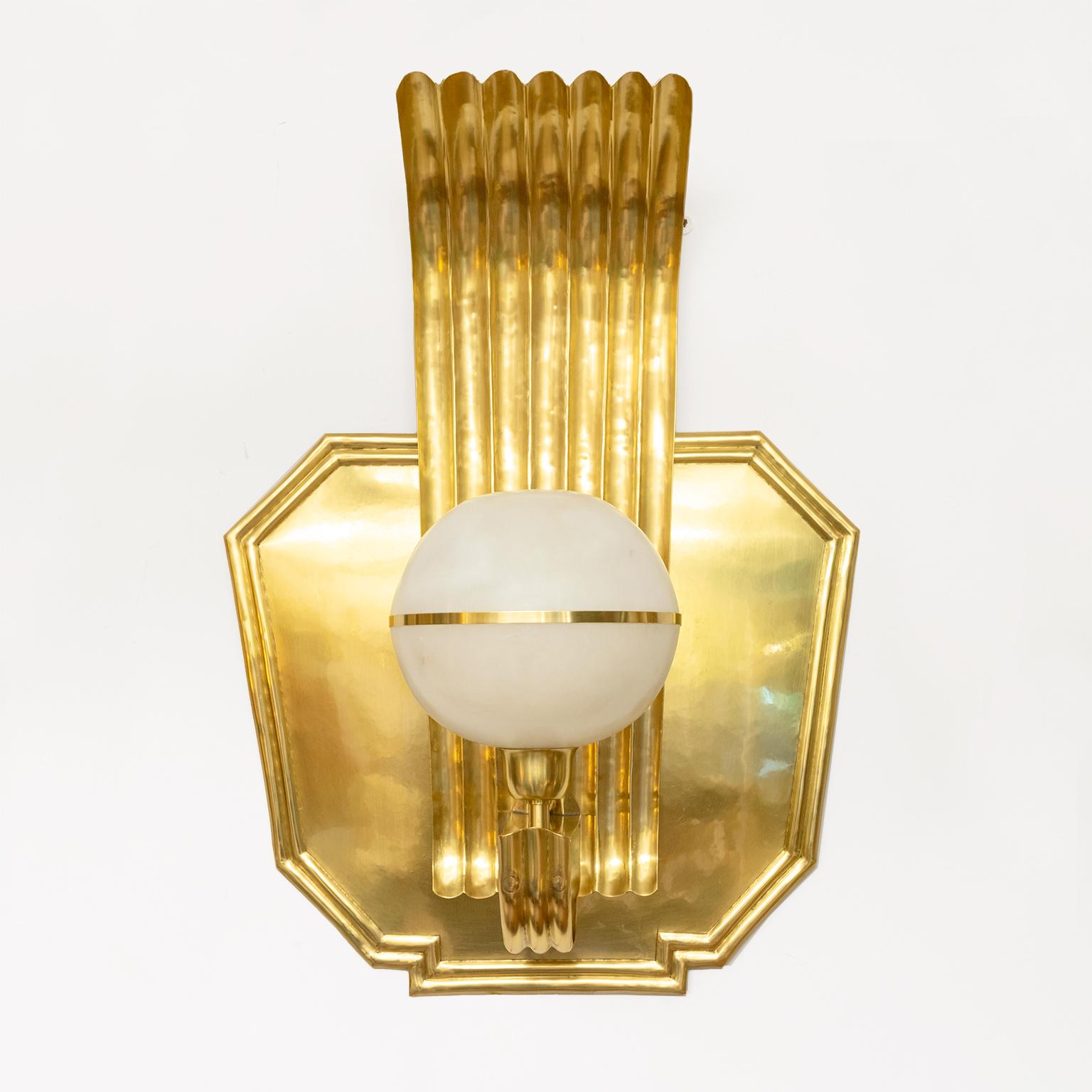 A Scandinavian Modern polished brass sconce with a carved alabaster globe shade. A great example of Swedish Art Deco this fixture has been fully restored, newly polished and lacquered. The globe contains a single standard base socket newly wired for