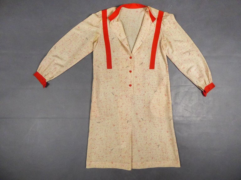 Circa 2006-2012

Blouse dress with printed Schiaparelli logo and dating from the brand's Renaissance in the 2010s. Loose, straight dress with buttons at the front, long puffed sleeves. Small red mandarin collar with reminder on the wrists and on two
