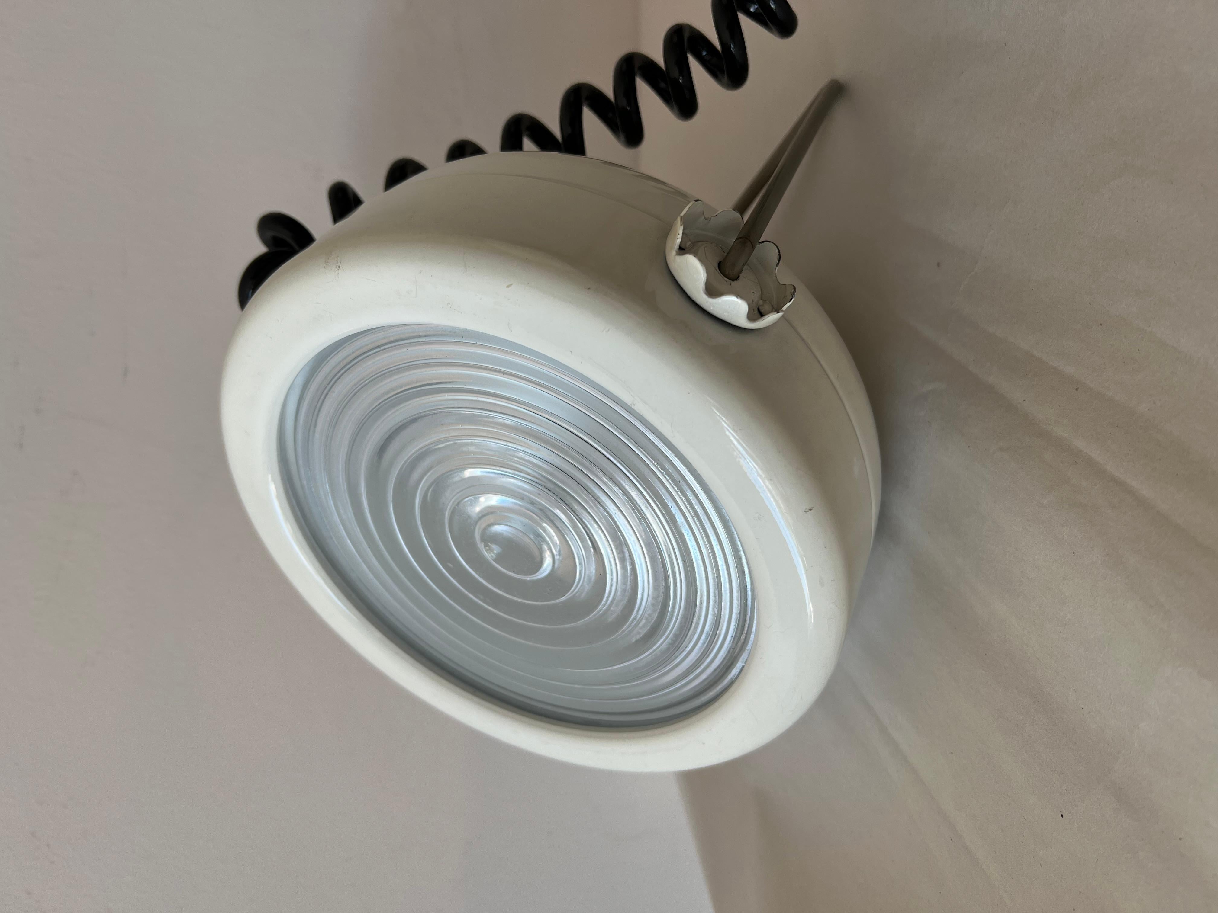 Una divertida lámpara de sobremesa o aplique diseñada por Achille & Pier Giacomo Castiglioni y producida por el fabricante italiano de iluminación Flos. La lámpara tiene un  Cuerpo metálico con dos engranajes que permiten que el soporte se bloquee