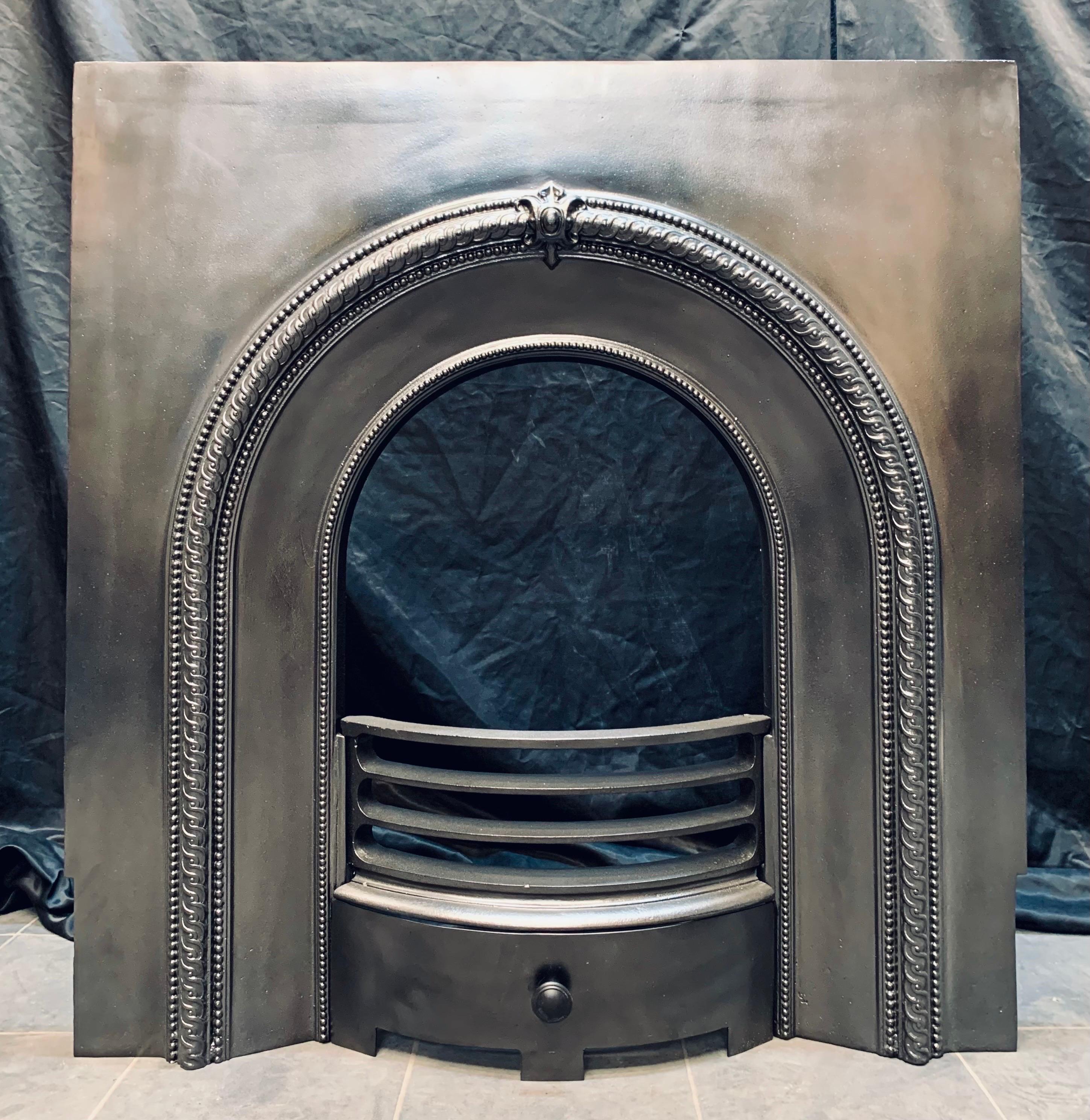 A Scottish 19th Century cast iron fireplace insert of good form. A generous outer plate, with a decorative high relief arched border a centralised cartouche. The three barred fire front with arched ash pan door. 

Inside opening arch size: 40cm wide