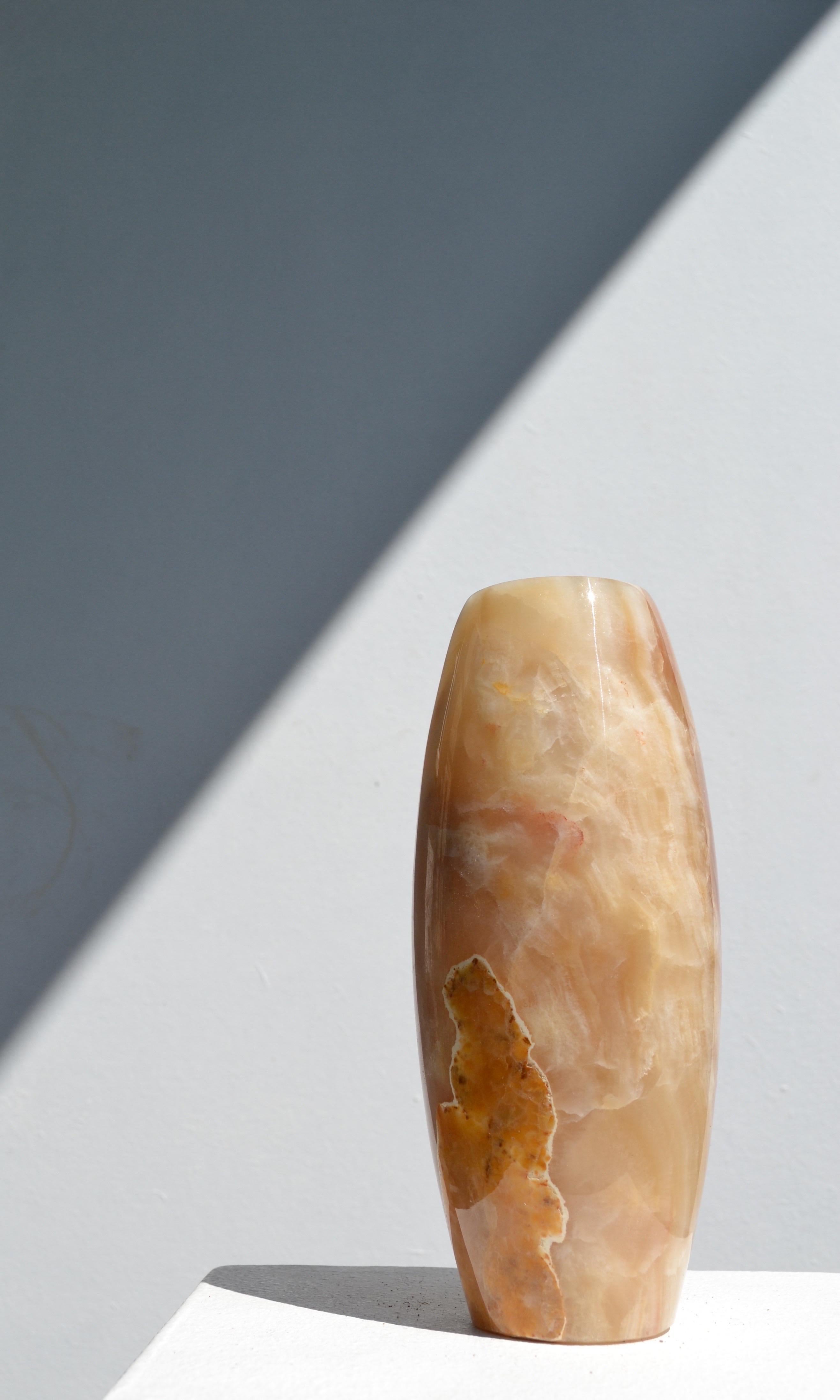 A striking oblong vase meticulously hand-carved from natural onyx, showcasing the stone’s rich veining and luminous depth. This sculptural piece balances organic form with refined craftsmanship, perfect as a centerpiece or decorative accent.