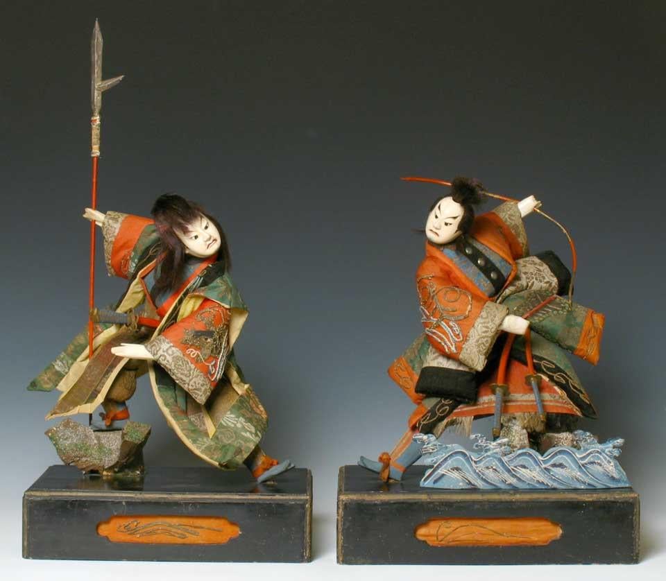 Japanese pair of Takeda Ningyo depicting two actors from a Kabuki play with brocade costumes and exaggerated positions, complimentary embroidered chirimen sleeves, one with a carp leaping from the waves and the other with an anchor and waves, one