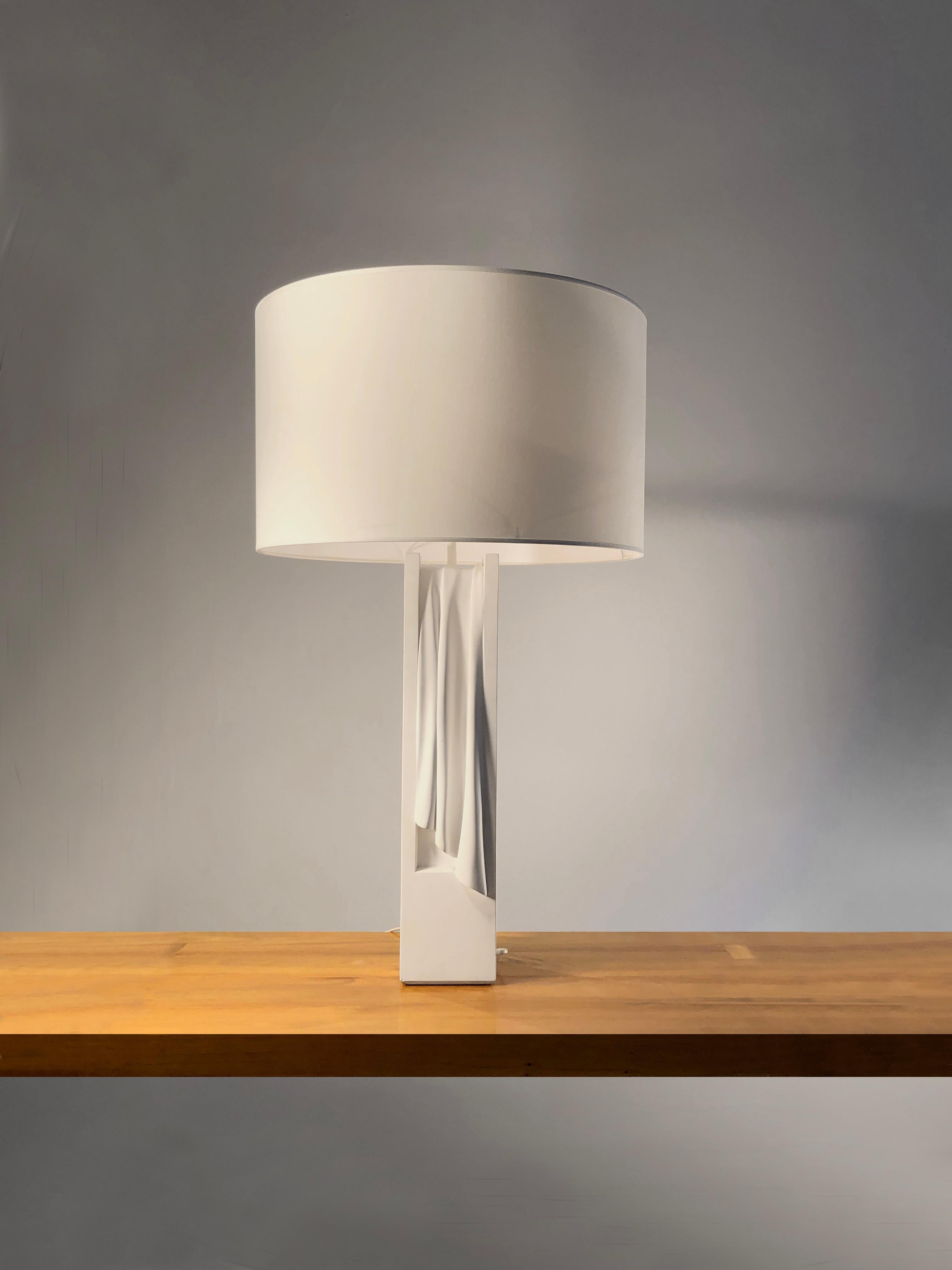 A rare spectacular and important sculptural table lamp, figuring a white curtain sculpted in a rectangular white block of plaster, coming with a minimal cylindrical white shade. This is an iconic model from the french eighties, designed by Loic