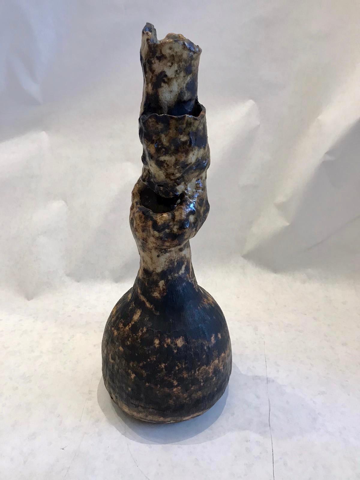 Lava glazed, extremely unique, this tall Studio Pottery vase has several openings to the sides of the neck piece. The large gourd-like base holds water for flowers, branches, etc. Earth tones and very chunky.