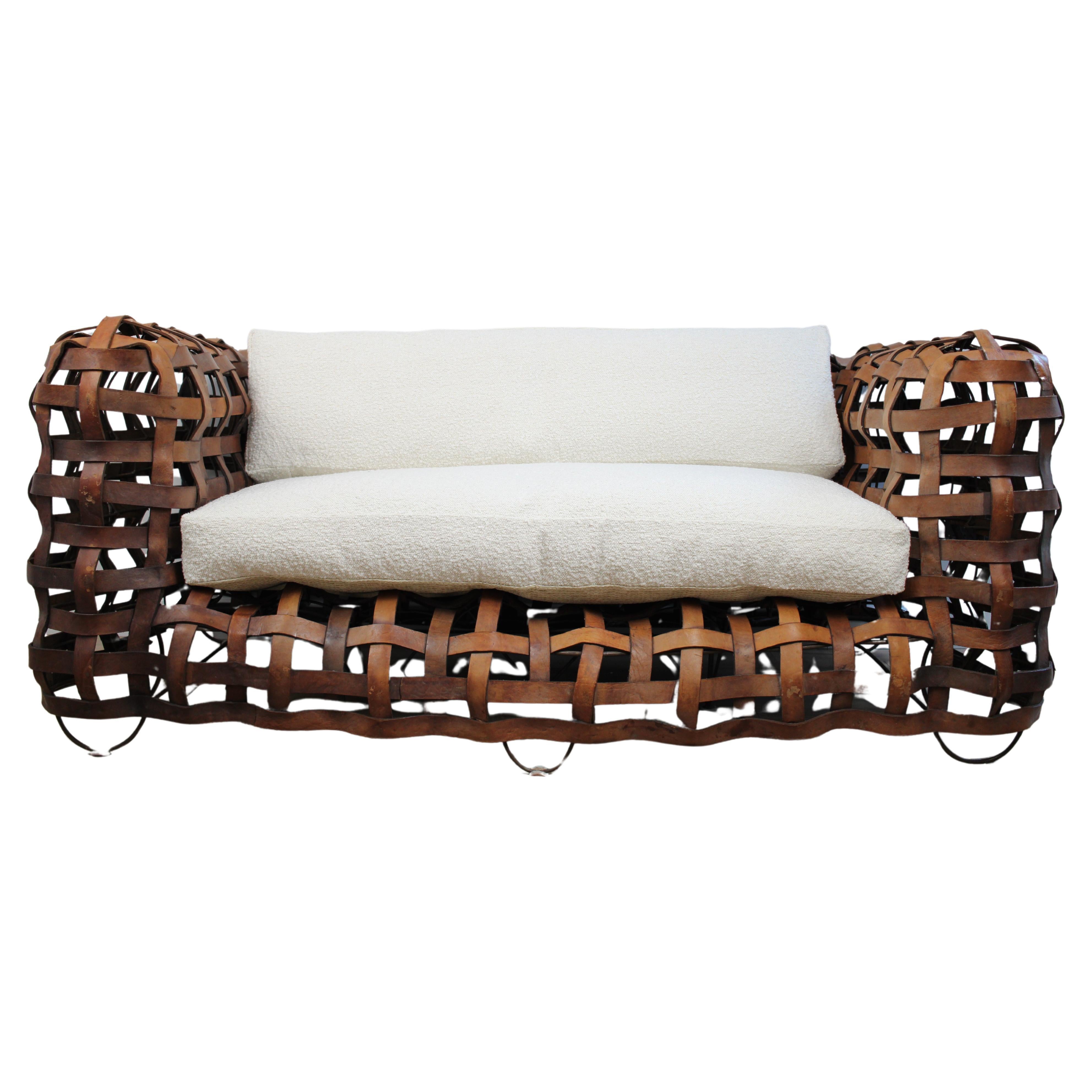 A sculptural Vintage woven leather strap sofa with feather cushions in boucle