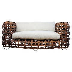 A sculptural Vintage woven leather strap sofa with feather cushions in boucle