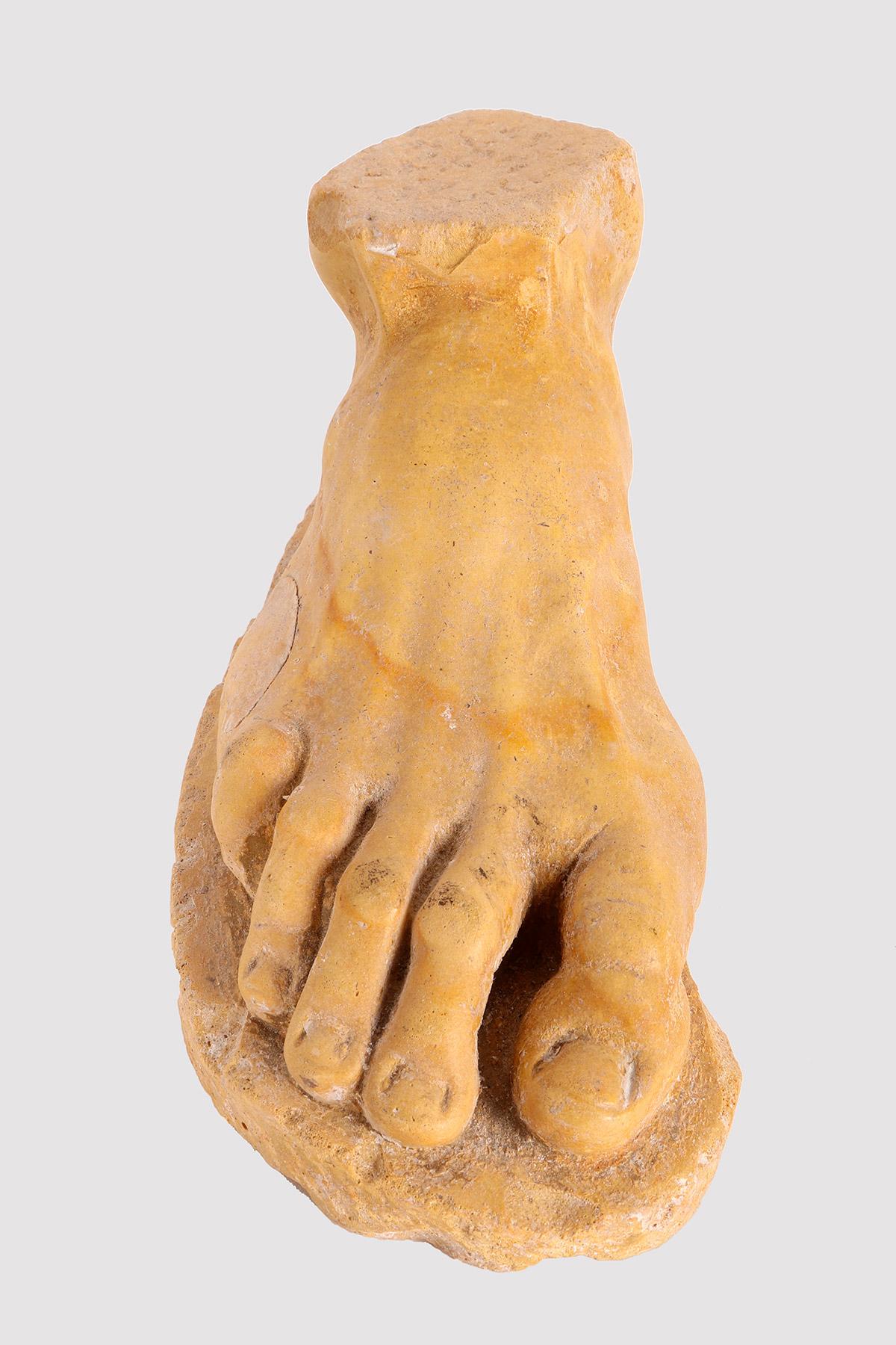 Scultura di un piede in marmo giallo di Siena. La scultura poggia su un terreno accennato. Replica di un tipo classico, la costruzione è eccellente, dalle proporzioni alla minima attenzione ai dettagli, come l'anatomia rilevabile sotto la pelle. Le