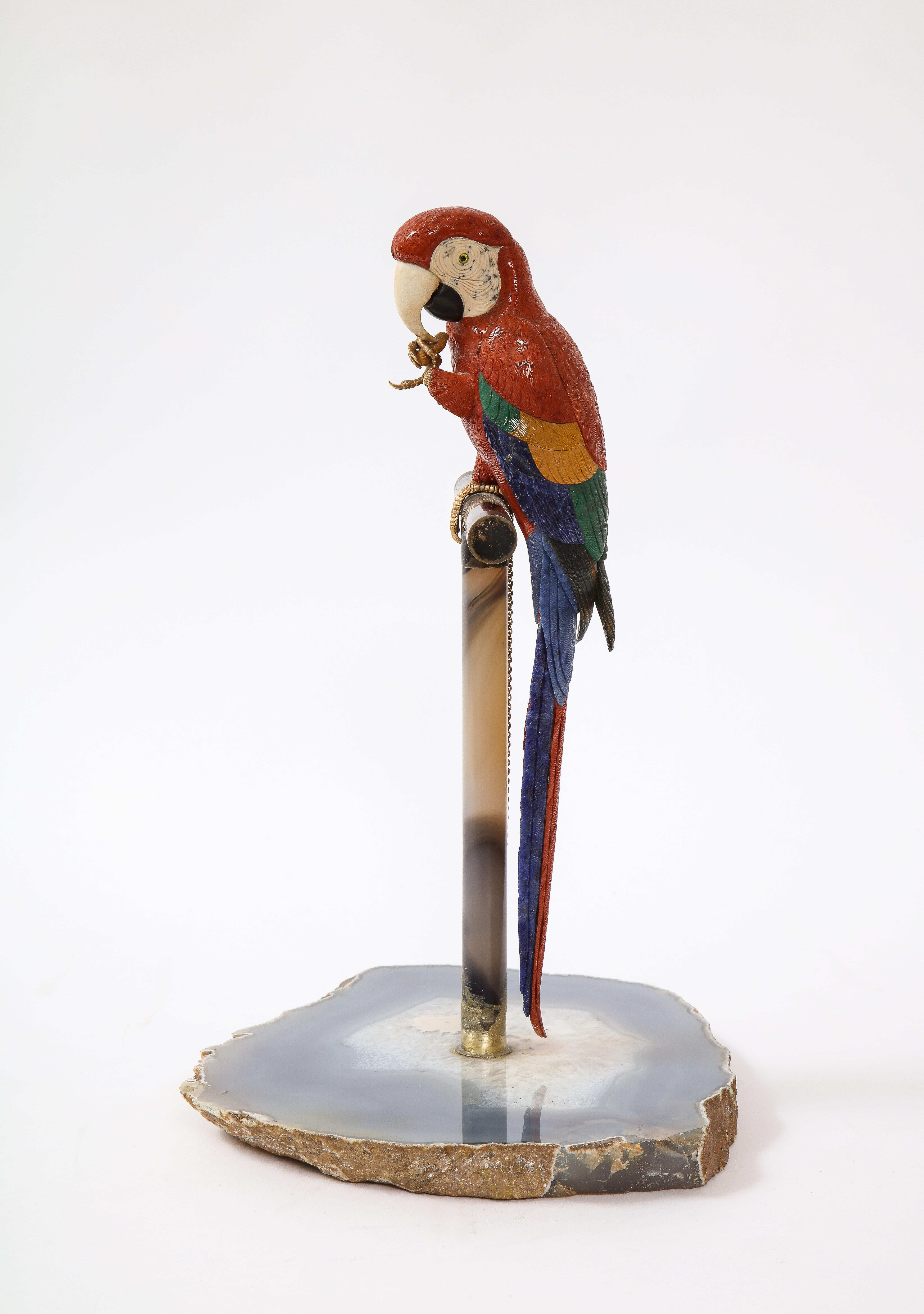 A fantastic Multi-Semi Precious Stone and Metal Mounted Model of a Scarlet Macaw Parrot, Attributed to Peter Müller, Swiss. This regal Scarlet Macaw is perched on a royal hand-carved agate pilar which rests on a sliced round agate slab. The