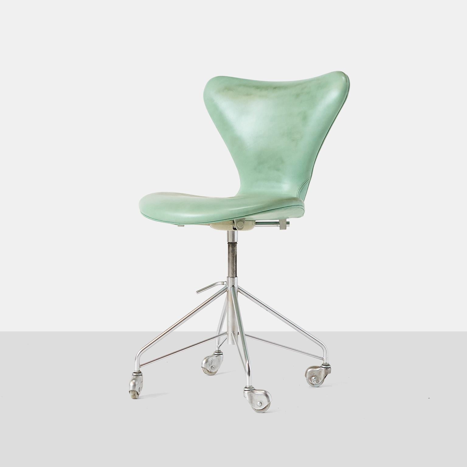 A series 7, model #3117, swivel base office chair with chromed steel feet on casters and an adjustable seat height Designed in 1955, this model has become the most popular design within Fritz Hansen’s chair collection This earlier example has been