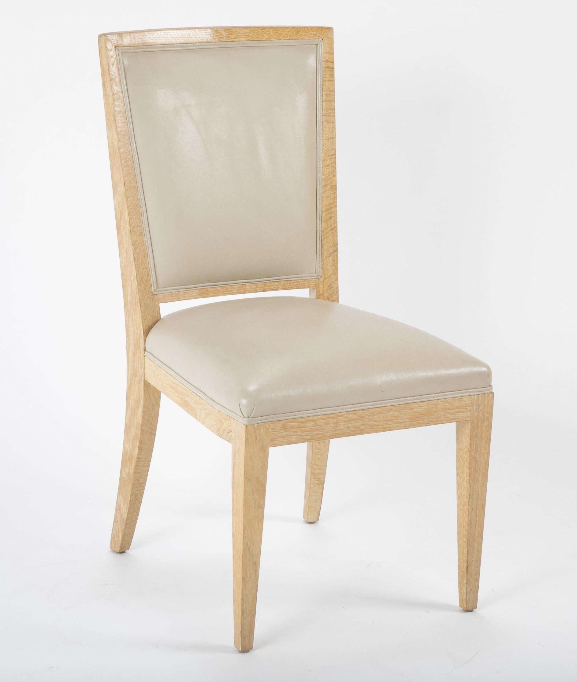 A striking set of 10 dining chairs. 8 side chairs and 2 armchairs with seats and interior backs cover in taupe leather. The chairs have grass cloth on the exterior arms and exterior backs.
  