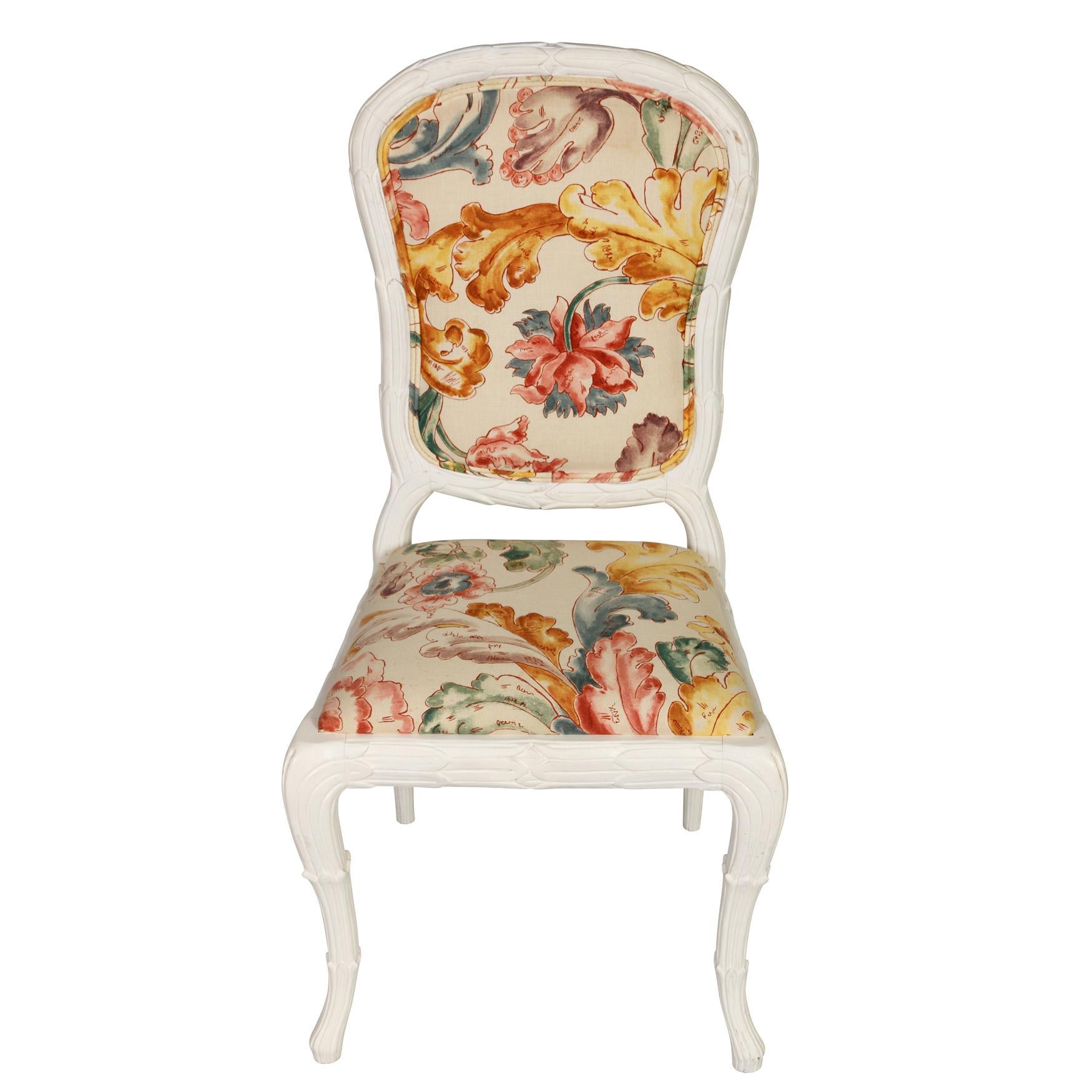 A pair of carved painted dining chairs with a lot of personality.  The set, consisting of two arm chairs and eight side chairs, have painted white frames, with lovely carved details.  The floral fabric is in excellent condition, but can easily be