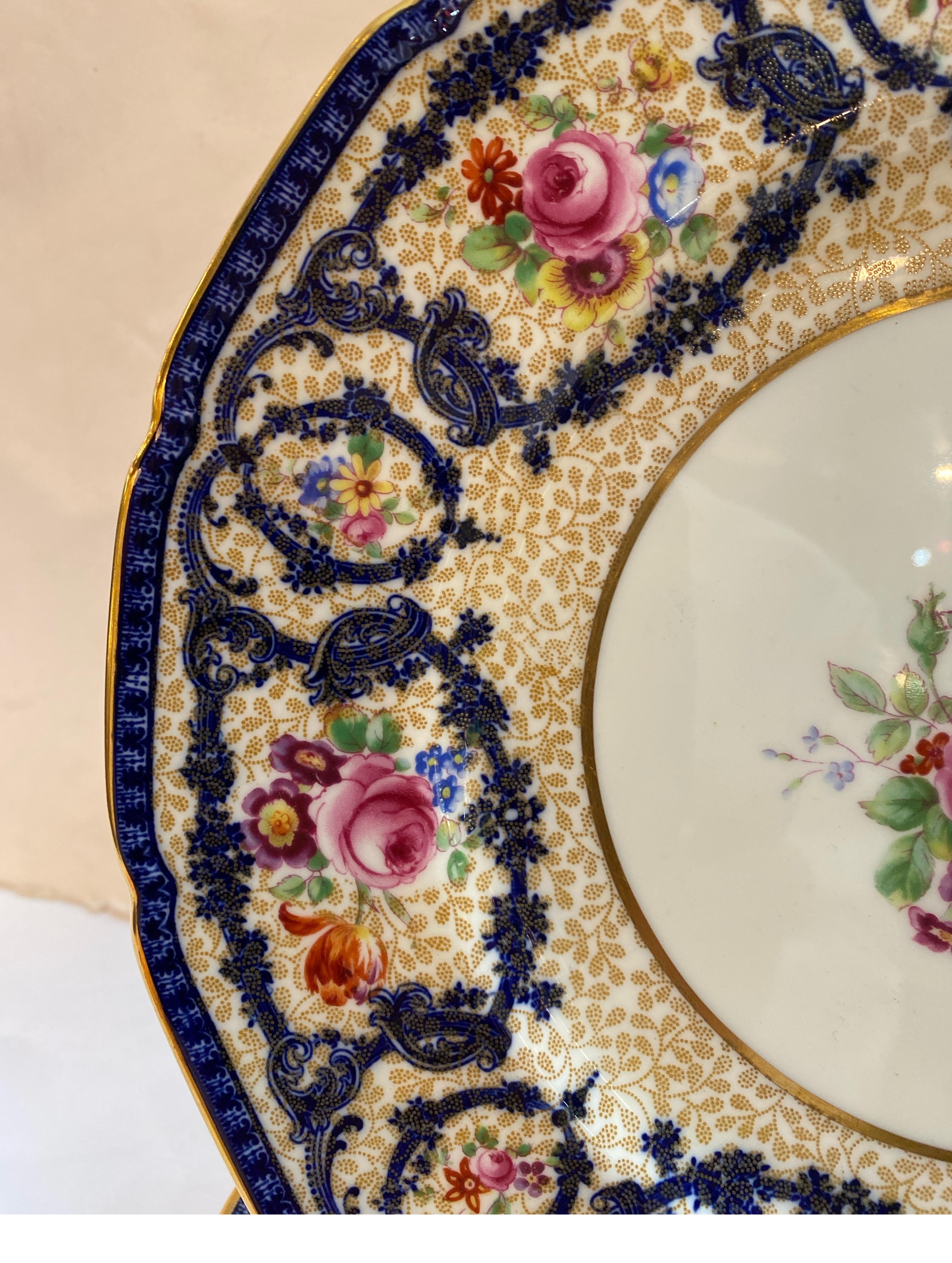 Ein eleganter Satz von 10 antiken Royal Doulton Service-Tellern, von dem bekannten Doulton-Künstler Robert Albert. Die Teller mit Wellenschliff und Goldrand haben eine zentrale handgemalte Blumenkartusche.  Die Platten mit einer frühen Marke auf der
