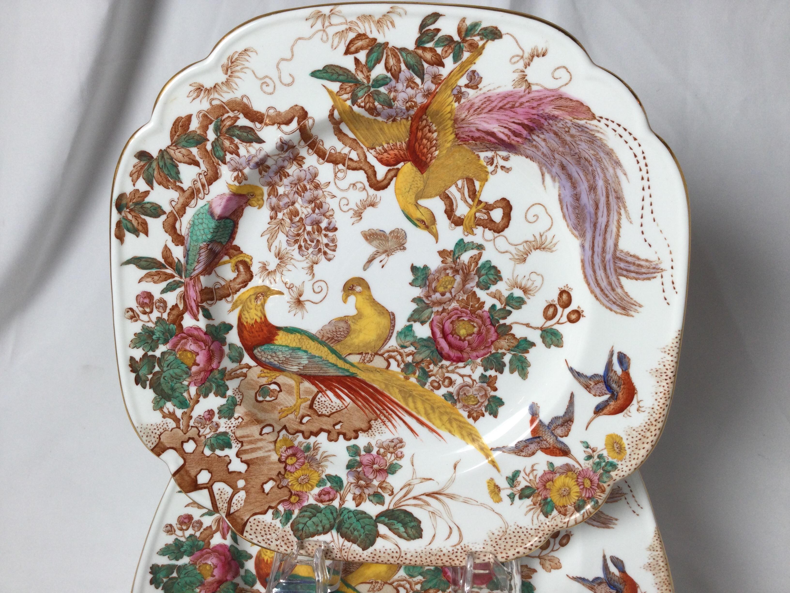 A set of vibrantly colored English luncheon plates by Royal Crown Derby. The plates depicting exotic birds on shapely branches hand colored in yellow pink and blue-green, circa 1930.