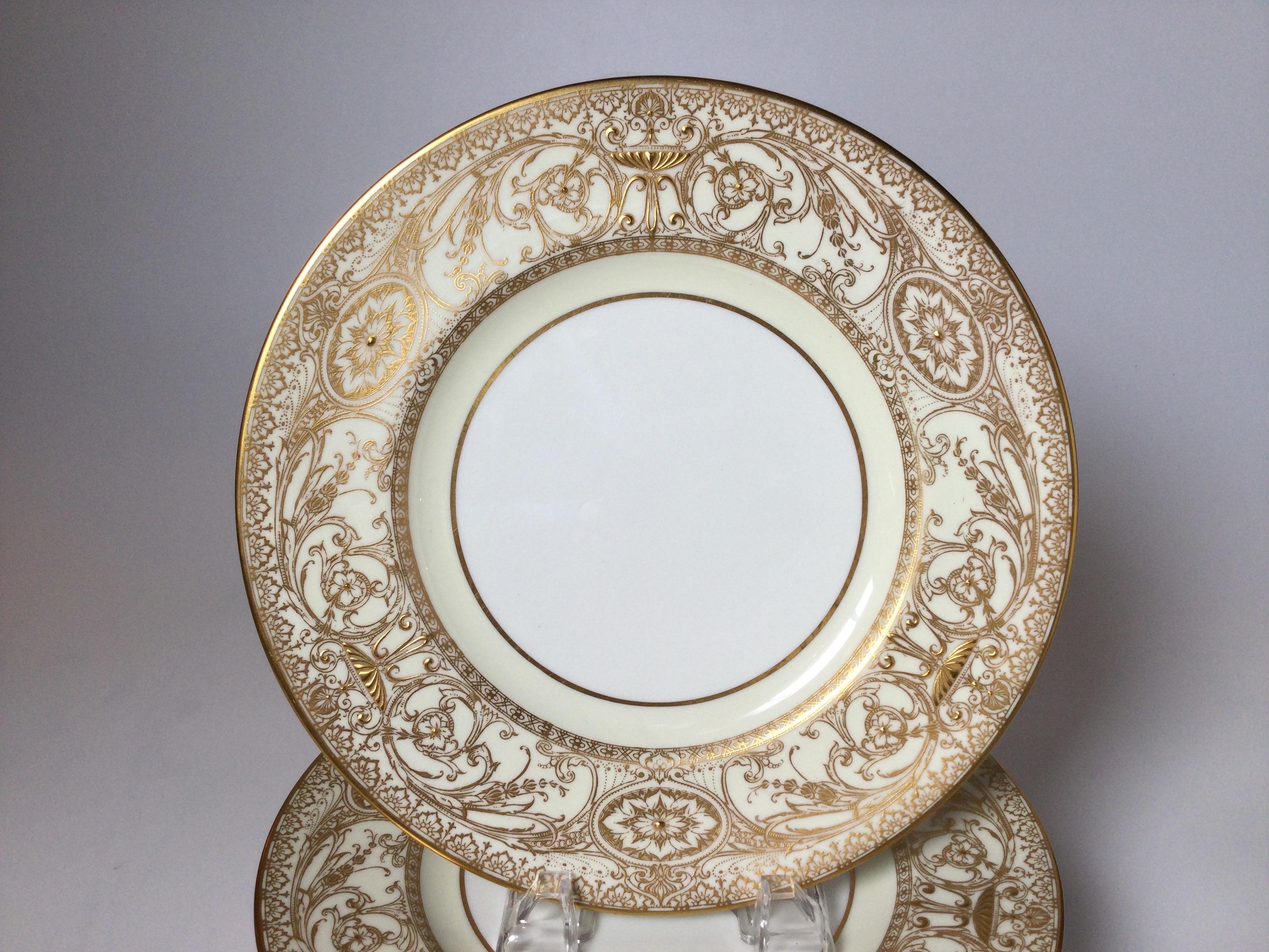 Un ensemble royal de 12 assiettes de service à la dorure élaborée, par Royal Worcester. L'ensemble est orné de larges et délicates bordures dorées sur fond de porcelaine blanche. La marque au dos date de 1950.