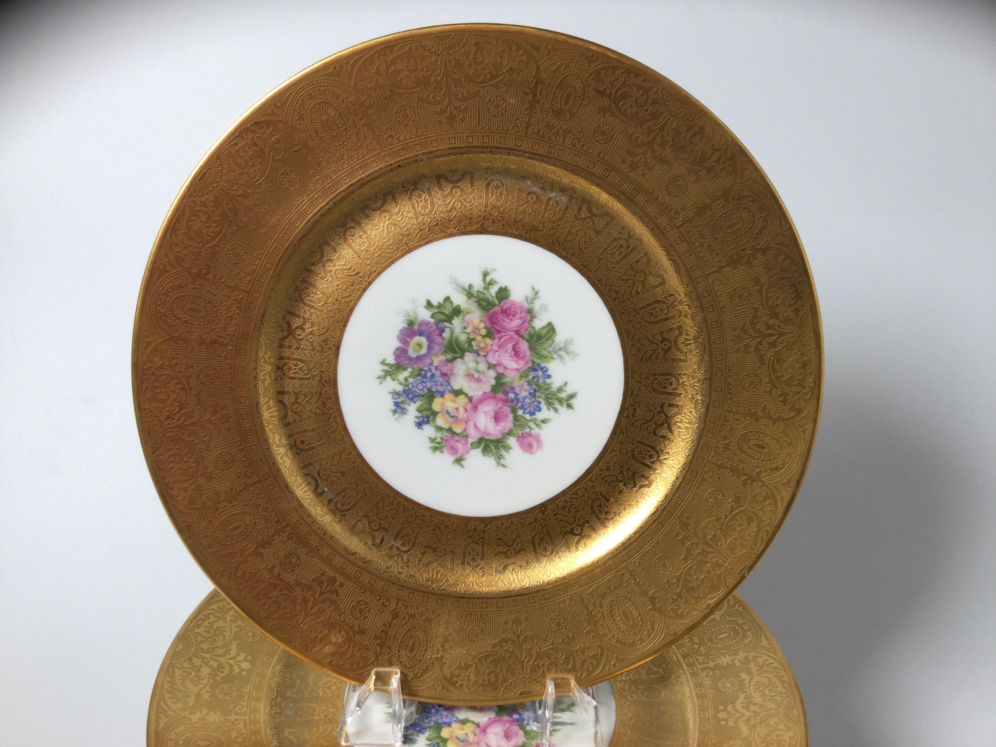 A set of 12 heavy gold banded floral service cabinet plates by Limoges, The detailed gold border with a delicate bouquet of flowers in the center cartouche. 10.5 inches in diameter.