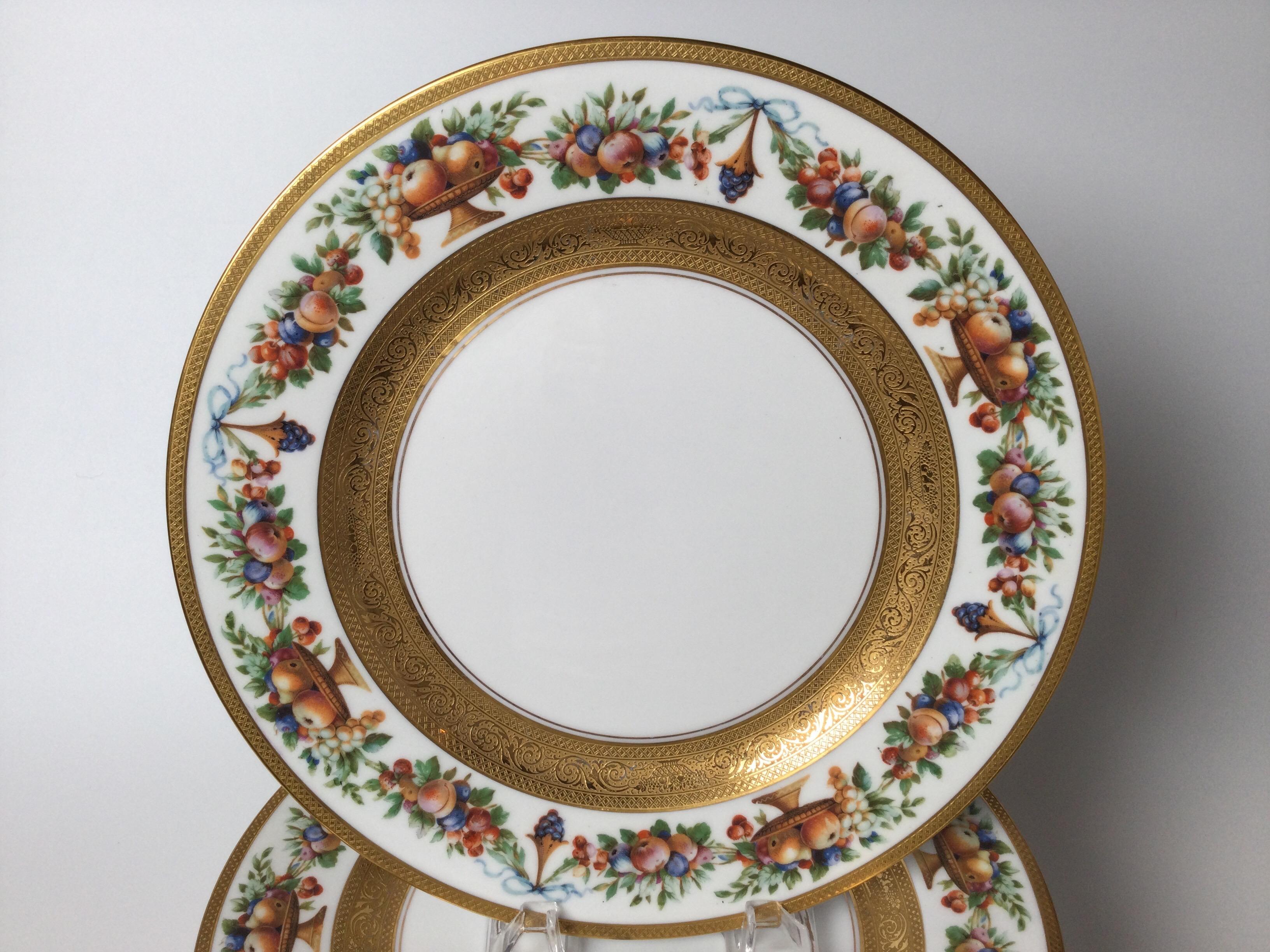 Set of 12 porcelain and gilt service plates. The decorative borders with swags and garlands of fruit with detailed gold bands on the edge and in the center.