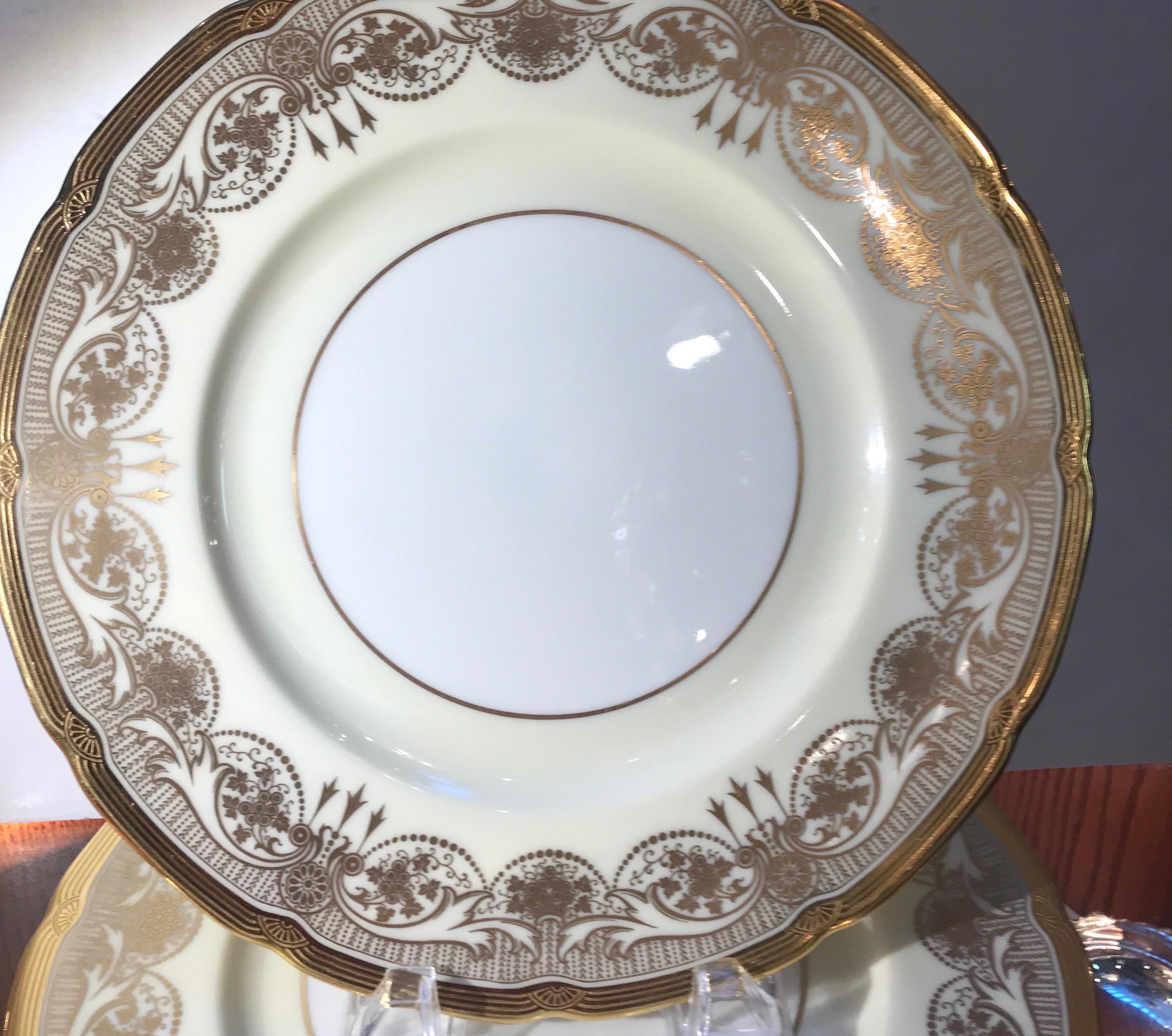 A Set of 12 elegant gold encrusted border dinner service plates. Each one with a fancy detailed gold border on a light vanilla cream background with an ivory white center. Marked on the back with an early Lenox green mark from 1930 or before. The