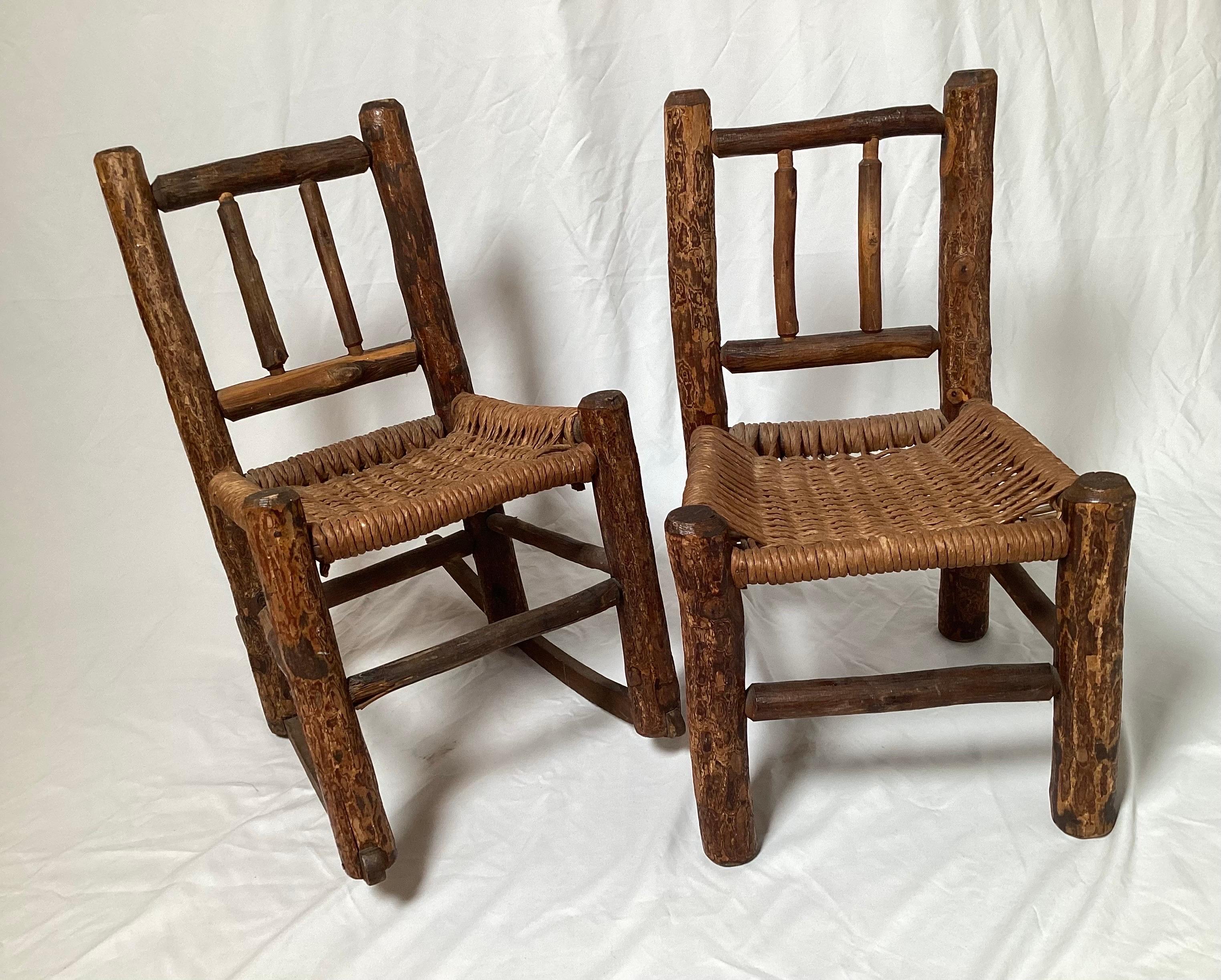 A set of 19th century Children's Adirondack chairs. The set includes one child's rocker and one child's side chair. The frame is made of lags with bark and the seats and back of woven rush