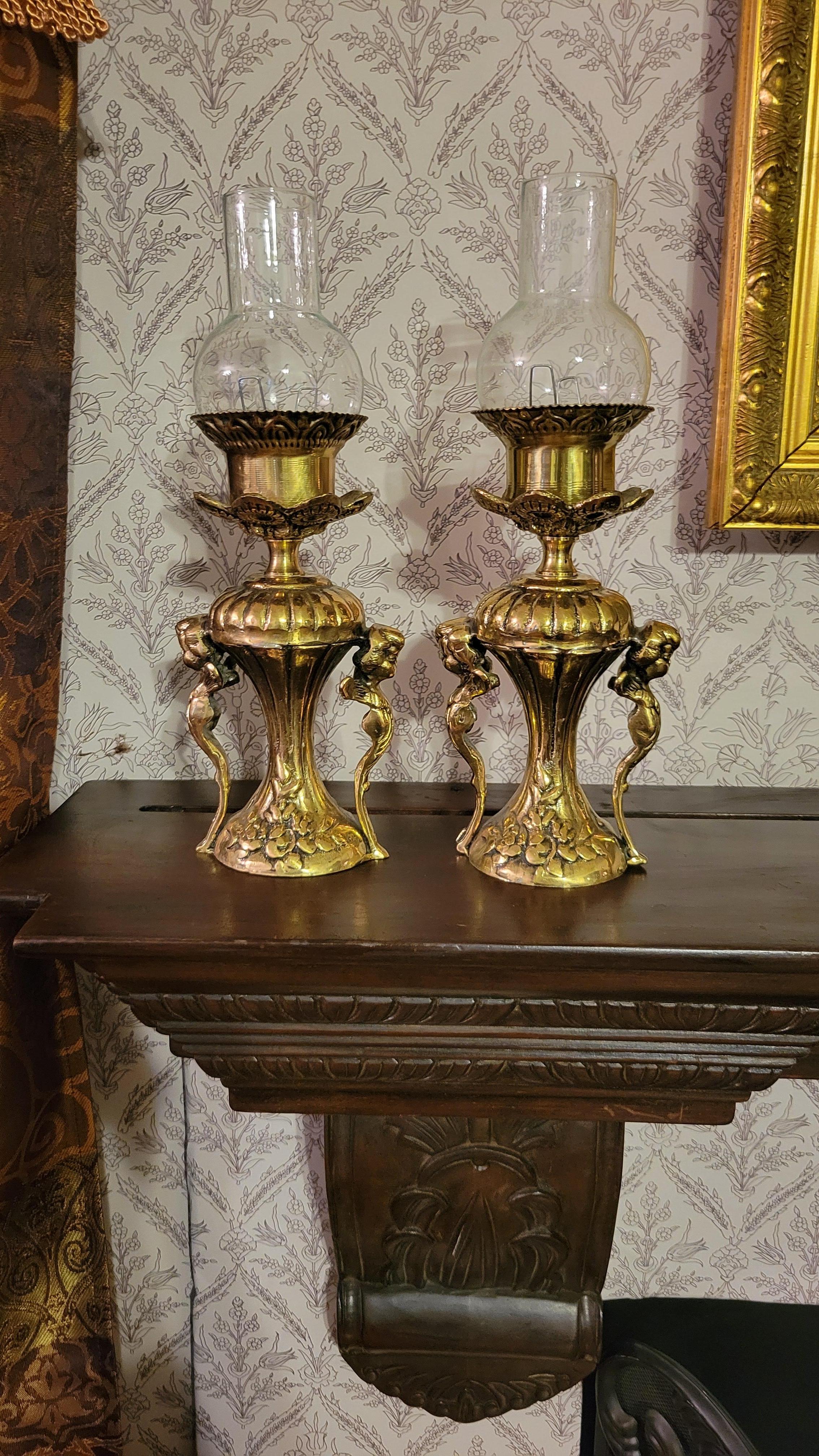 A set of (2) solid brass antique style lamps with globe chimneys. The lamps feature antique design with cherubs on each side.
The lamps look like candle-holders and probably could be used this way, but 
they were designed for wiring.
Please