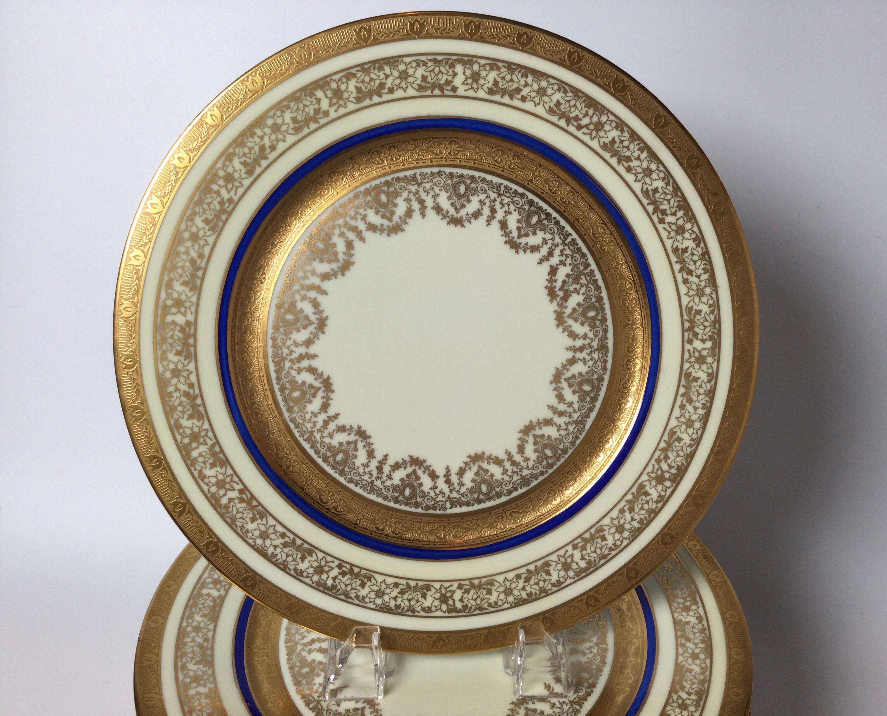 Elegant set of 12 gilt porcelain service plates with cobalt blue band. The several bands of gold with a thin cobalt band on a bone color porcelain plate. Retailed by Ovington Brothers, NYC.