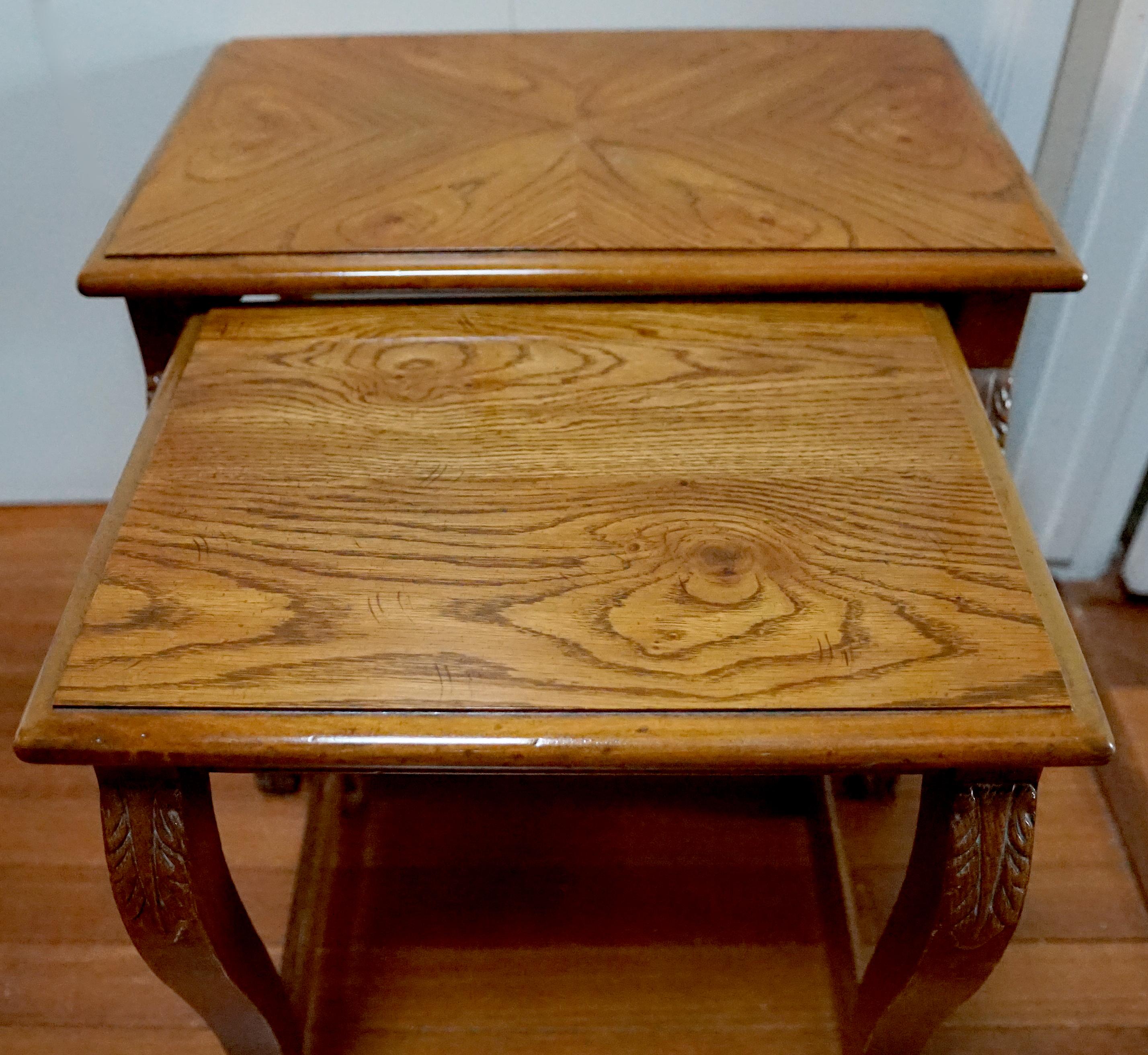 This is a charming pair of nesting tables. The waterleaf or anthemion carving at the tops and bottoms of the legs is a really nice touch. But they are not just beautiful, they are useful as well. 
The pair are Classical or Empire style oak tables In