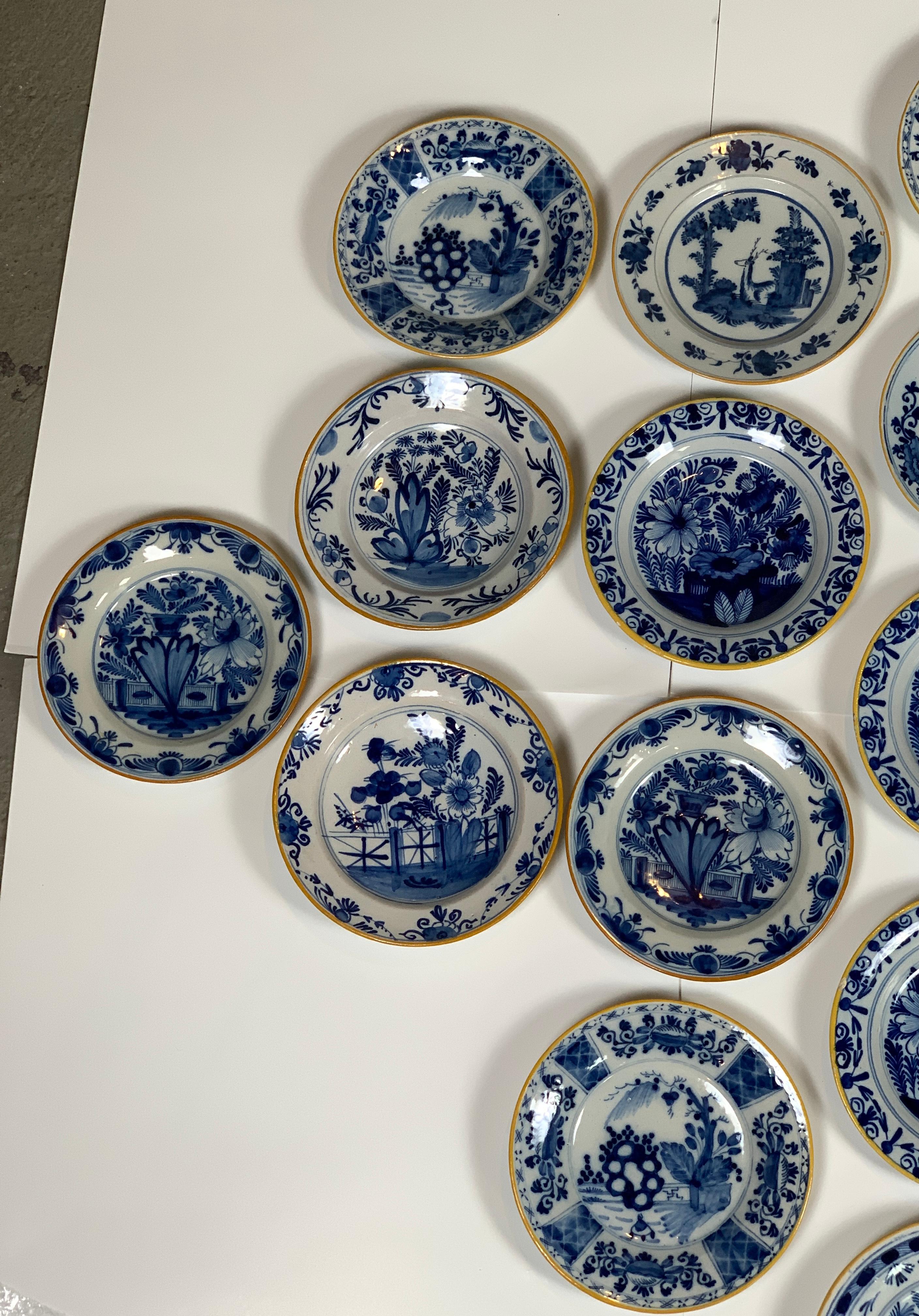 Twenty-one blue and white Dutch Delft dishes hand-painted in the 18th and very early 19th century showing a variety of traditional scenes, including a deer in the forest, floral bouquets, and gardens overflowing with peonies and other flowers (see