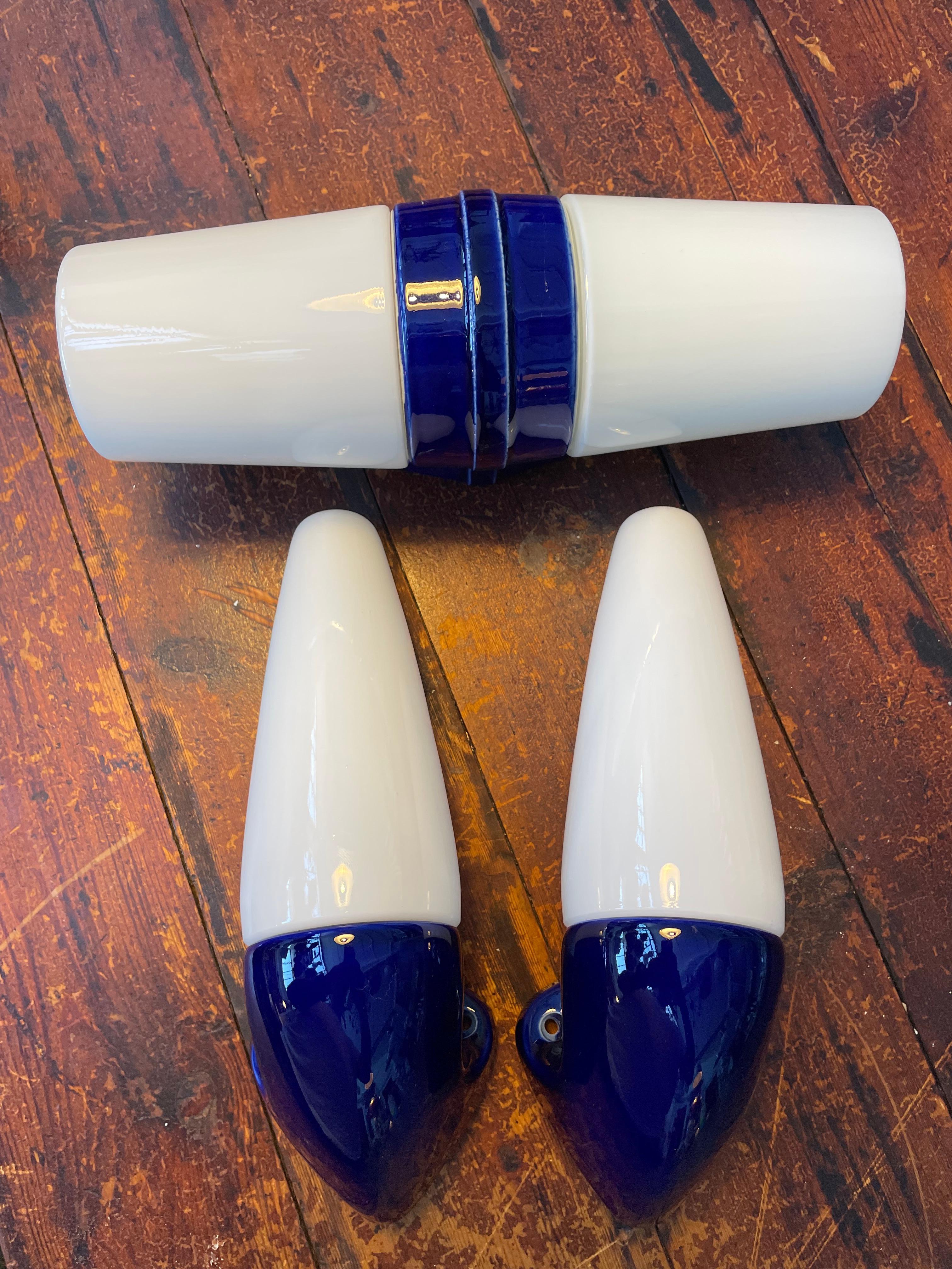A set of 3 vintage Ifö of Sweden ceramic bathroom lamps from the 1960s in dark blue.
Two model 6035 and one model 6065. 
Designed by Sigvard Bernadotte. 
Opaline glass shades. 
Ceramic bulb holders for an E14 bulb model 6035 and E27 for Mendel 6065.