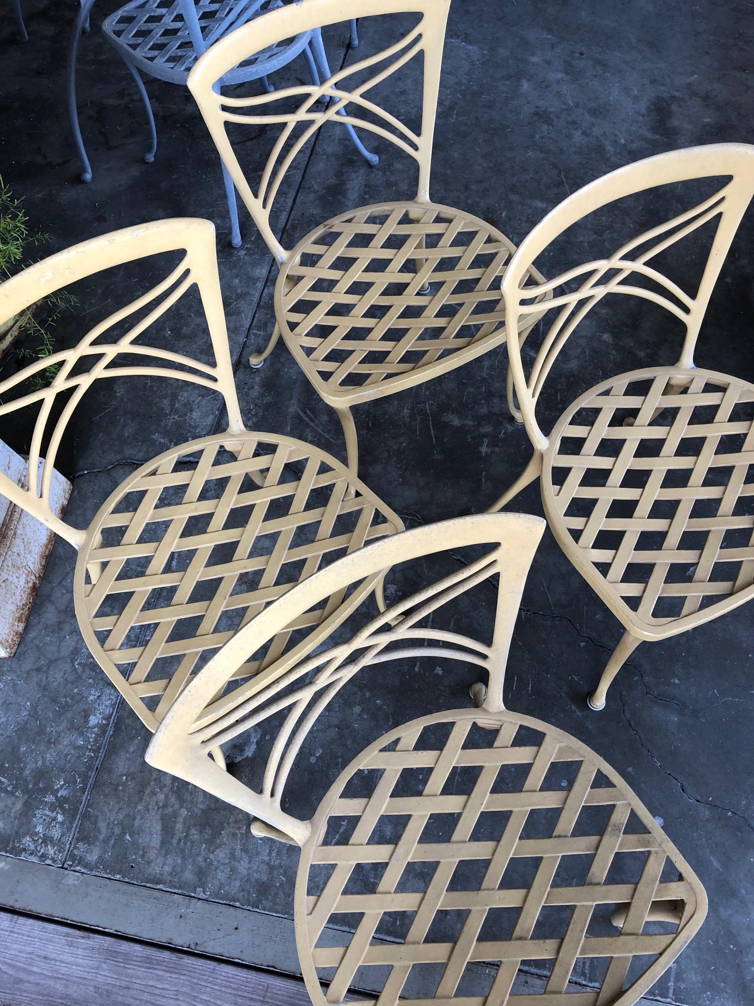 A stylish set of 4 American 1960's yellow-painted aluminum garden chairs by Brown Jordan; each with openwork back and x-form splat above a generous strapwork set; all raised on graceful splayed legs