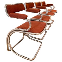 A set of 4 cantilevered chrome chairs with a burnt red orange tweed fabric