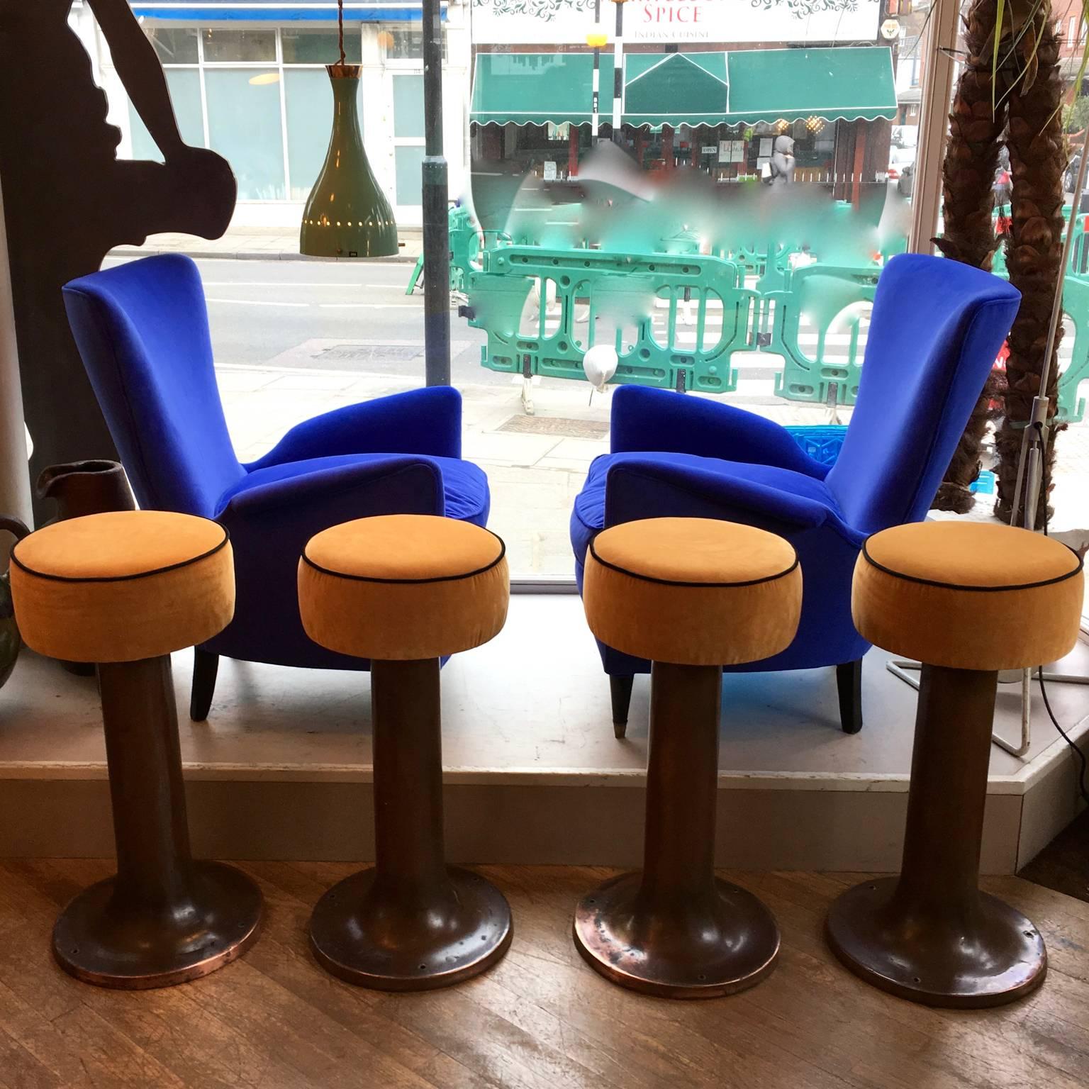 A rare and very unusual set of four bar stools with copper bases and orange yellow velours seats. They were salvaged from an Italian ocean liner. Heavy and unusual, they can be fixed to the floorboards in a boat (the original bolts are still