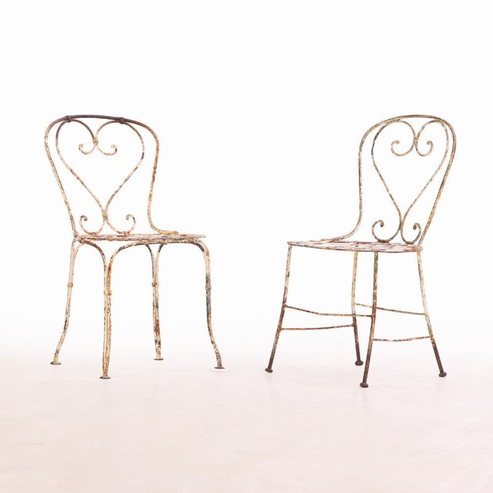 Charmant ensemble de quatre chaises de jardin françaises, vers 1950, fabriquées en fer forgé avec de gracieux détails de volutes ouvertes. Les lignes curvilignes et la construction aérée évoquent le design classique des jardins français, offrant à