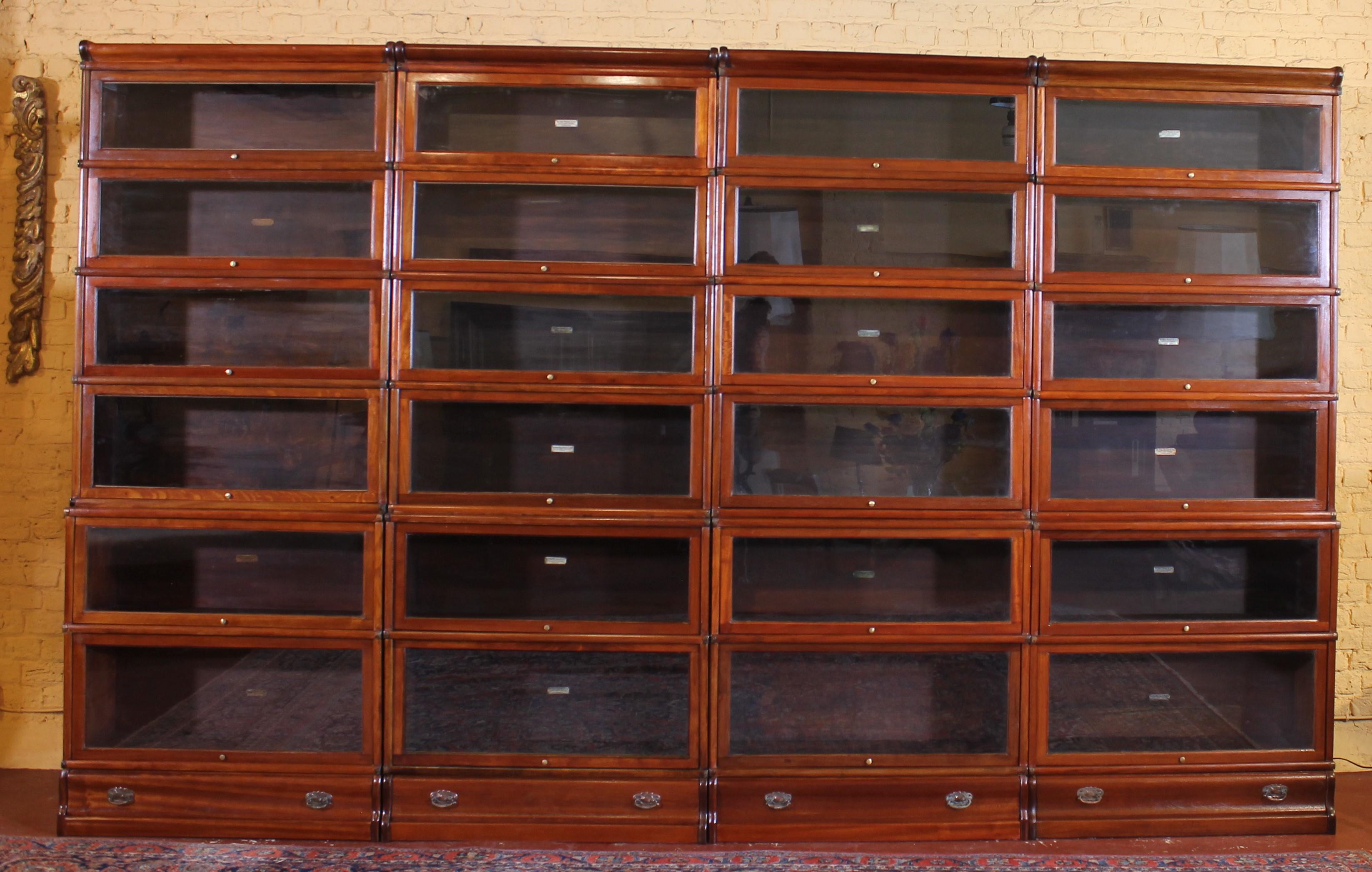 Elegant set of four large Globe Wernicke London mahogany bookcases from the end of the 19th century - Early 20th century from England which have two lower advanced part (the two lower elements are deeper) as well as a drawer in their base

The four