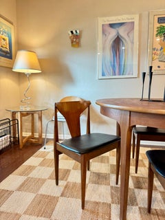 A set of 4 mid century modern dining chairs in teak with black faux leather