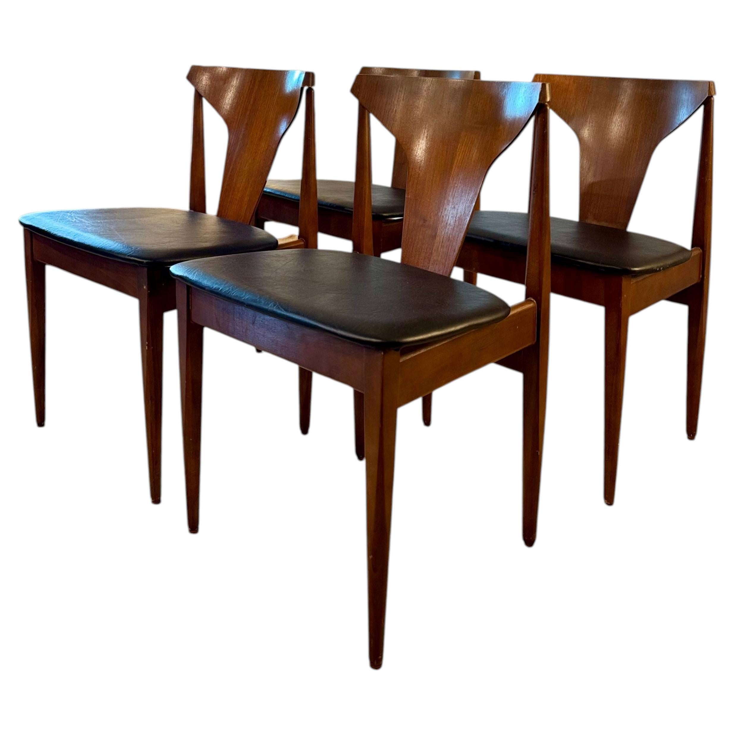 A set of 4 mid century modern dining chairs in teak with black faux leather