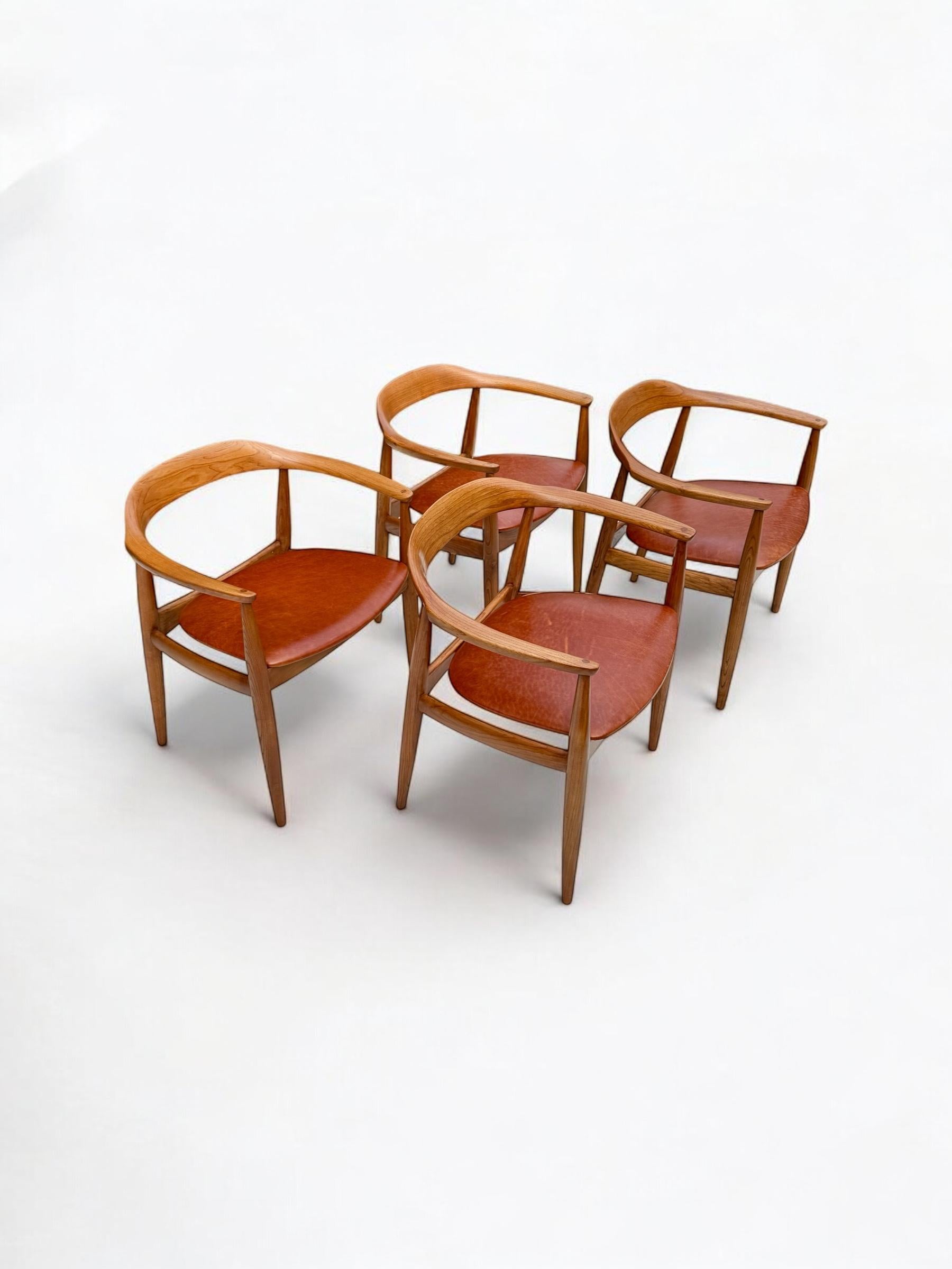 This rare set of armchairs/carvers by Illum Wikkelso for Niels Eilers, are truly iconic in design and form crafted out of Elm wood the seats re upholstered in a charming Cognac leather. The chairs are very versatile they may be used as dining chairs