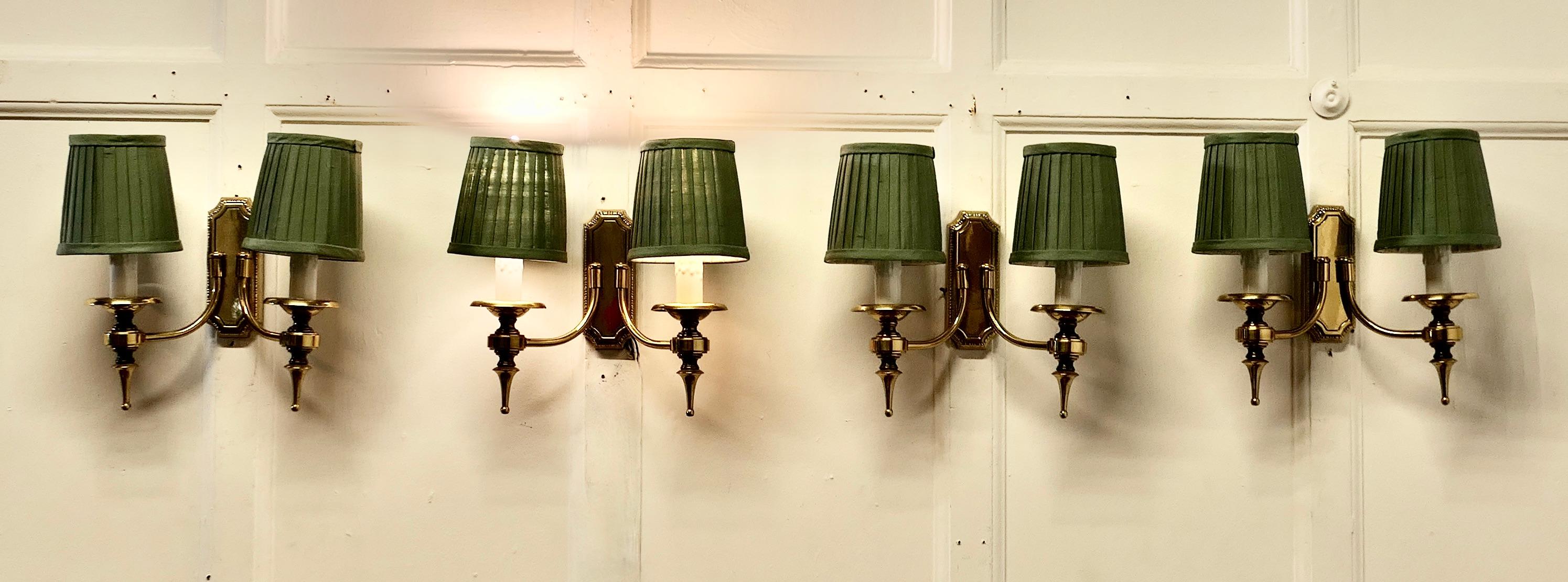 A Set of 4 Twin Wall Lights

A very handsome set of 4 double wall lights, the lights are in brass in an attractive designed with ceramic simulated candles and pleated shades in Teal/Grey 
The lights are in good and working condition, the will have