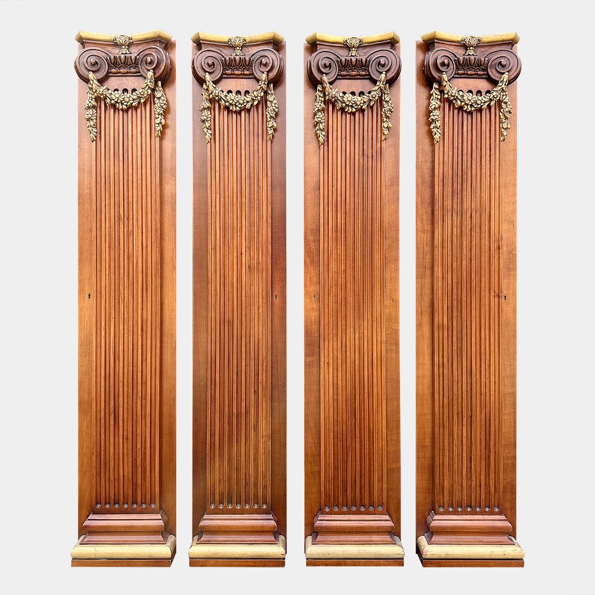 A set of 4 reclaimed pilasters with gilt wood carved capitals and gilt socles. 
The fluted pilasters with carved  gilt floral drapery hung from Ionic capitals.
These were used as doors to hidden spaces in a library. At just over 6ft tall and 1ft