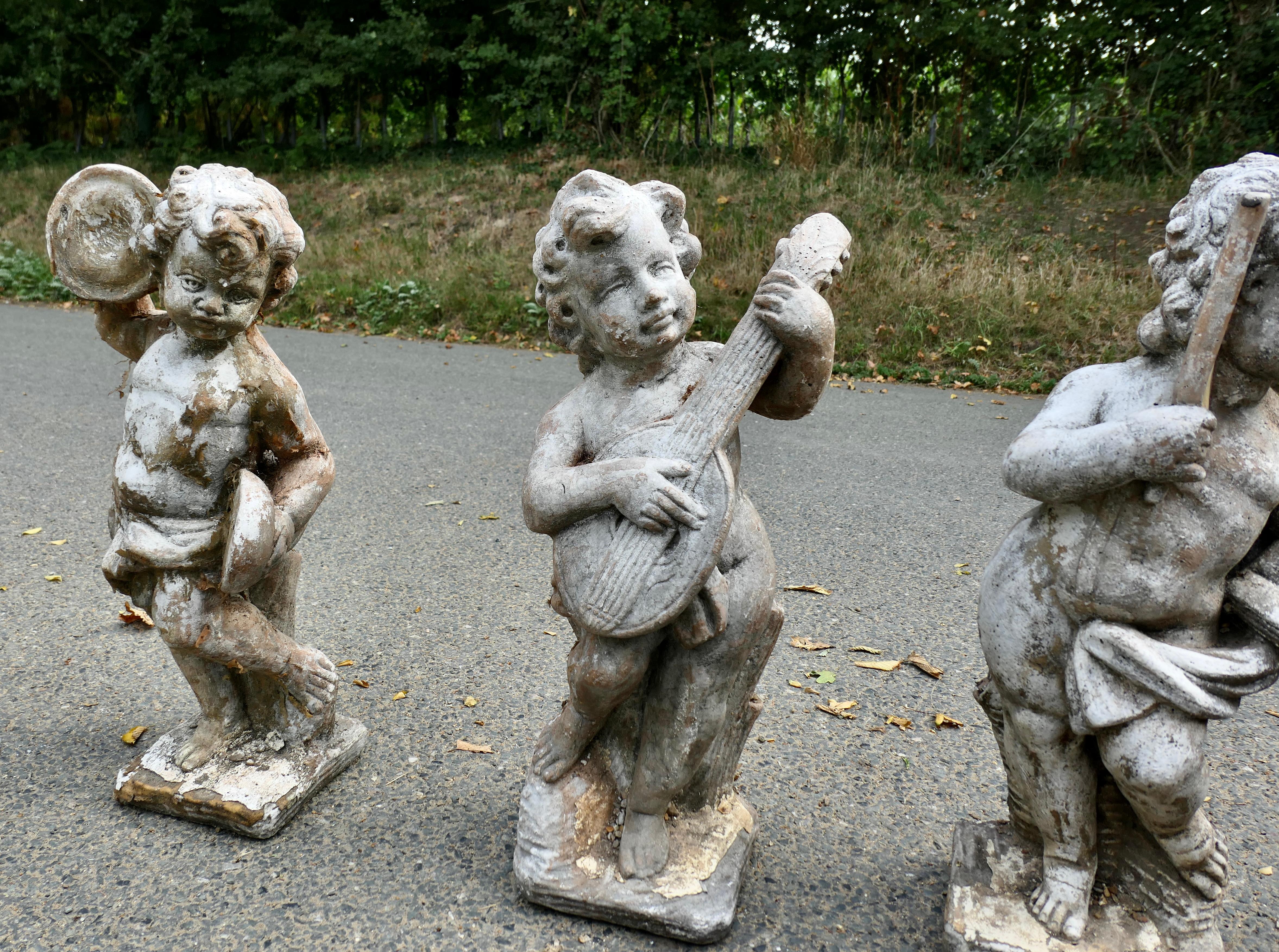 A Set of 4 Weather Worn Cherub Statues with Instruments  This is a wonderful set In Good Condition For Sale In Godshill, Isle of Wight