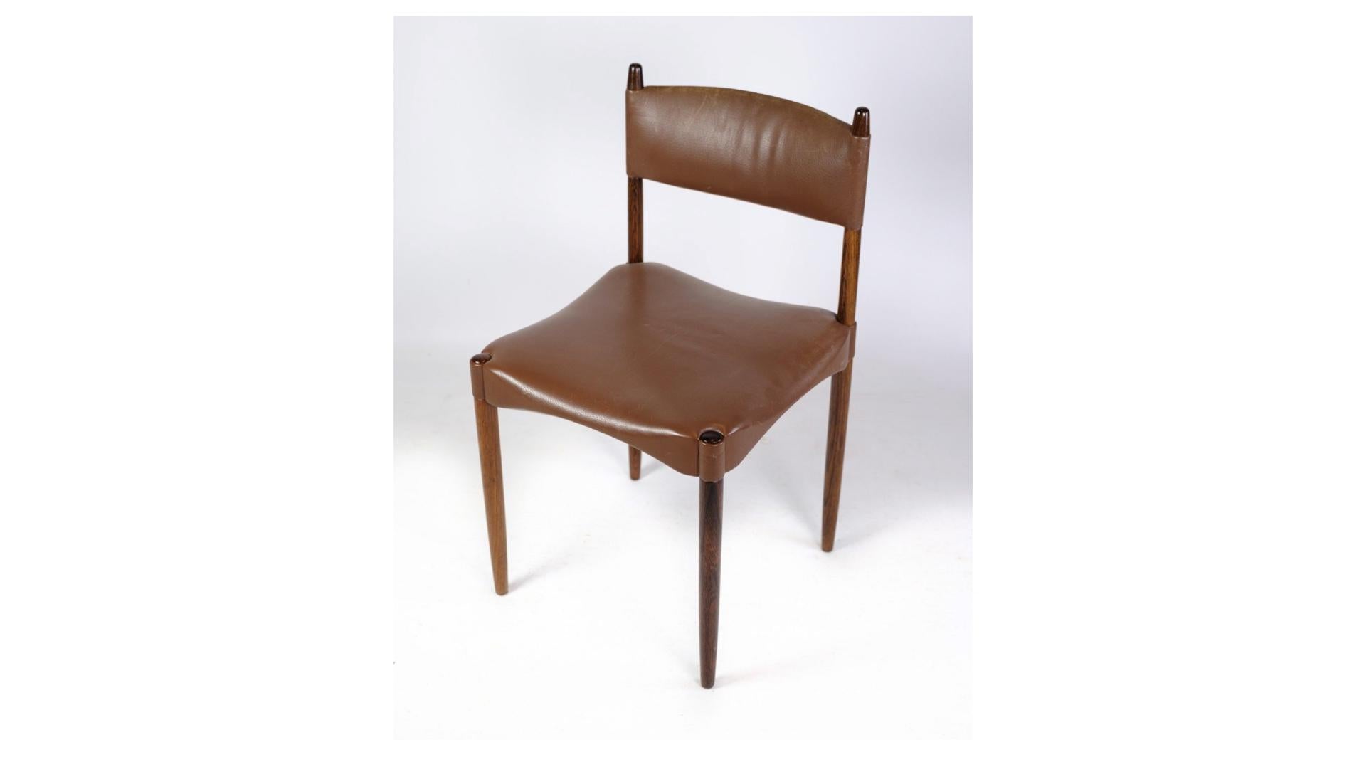 Cet ensemble de six chaises, fabriquées en bois de rose massif et revêtues d'un riche cuir brun, incarne l'élégance et le savoir-faire du design danois du milieu du siècle.

Les chaises présentent une silhouette intemporelle aux lignes épurées et